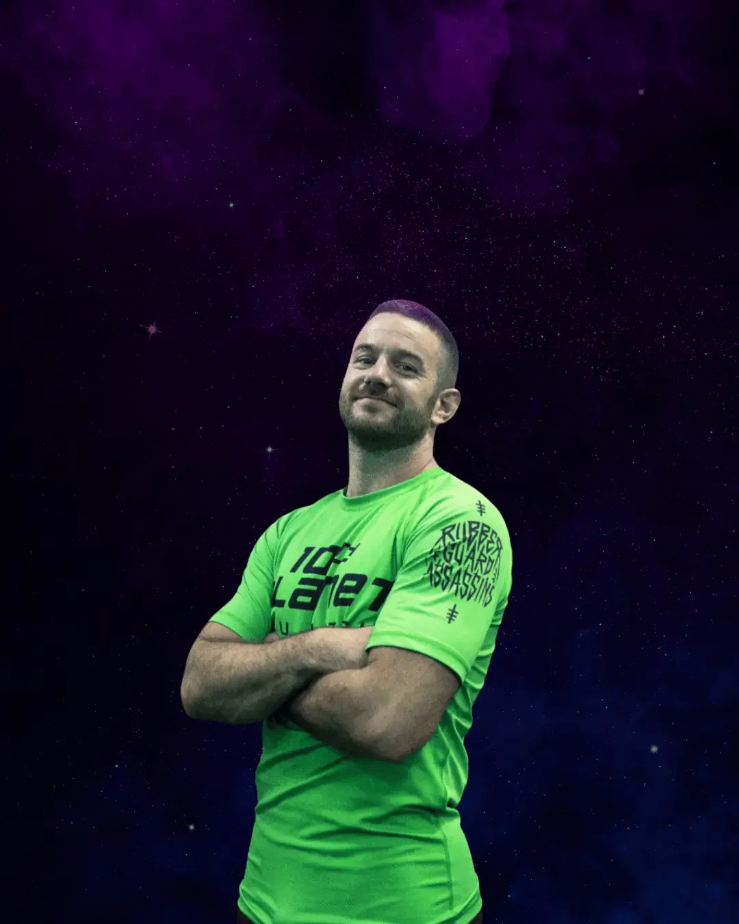 A man with a short beard and short hair, smiling confidently with arms crossed, wearing a bright green sports shirt with black text and a design on the sleeve, standing against a starry outer space background with purple nebula clouds.