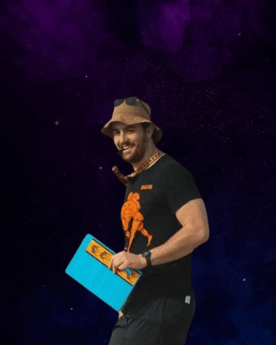 A smiling man in a space-themed background, wearing a hat, sunglasses on the hat, a black t-shirt with an orange graphic, carrying a blue folder.