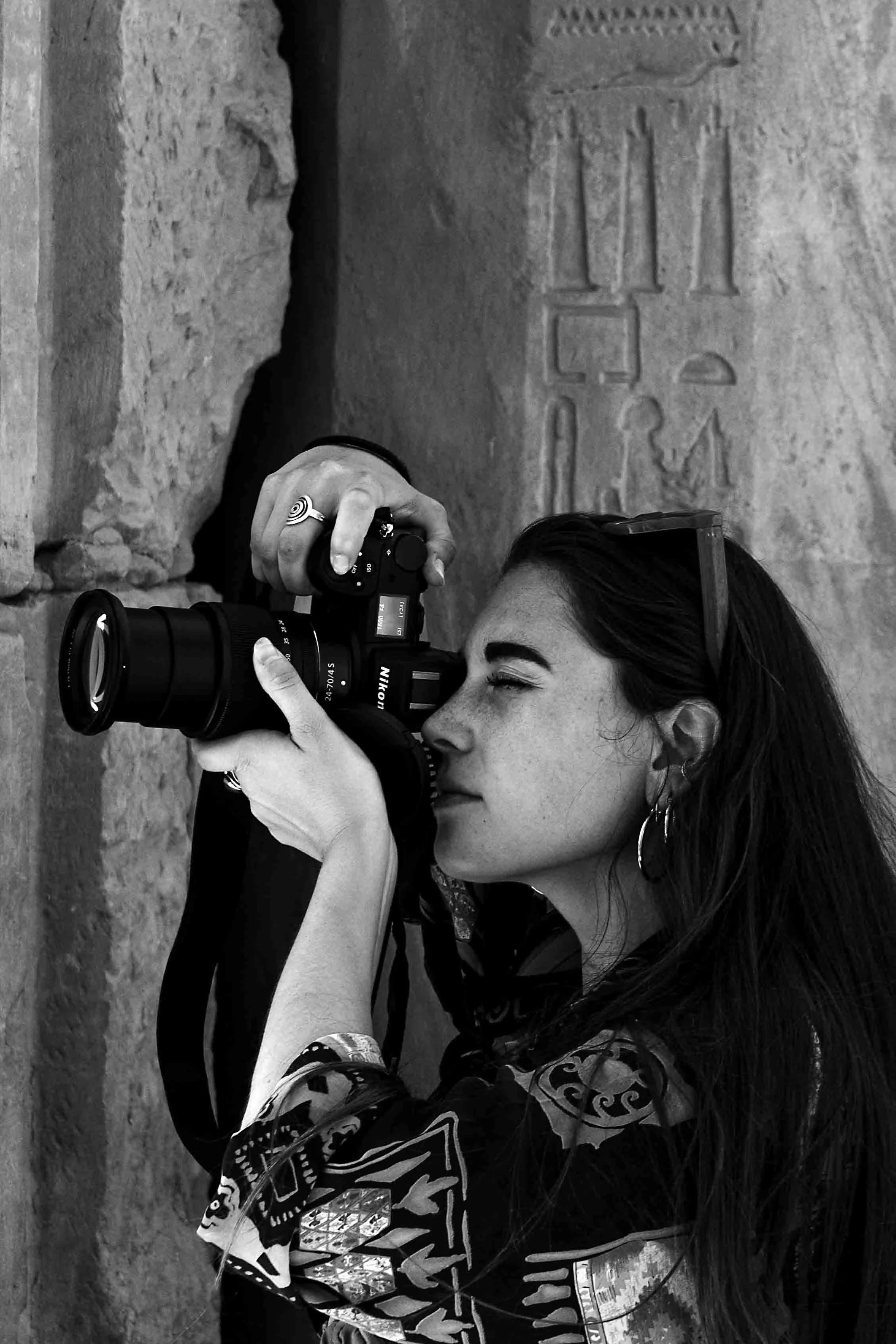 Capucine Lambrey regardant dans l’objectif d’un appareil photo, illustrant ses prestations photographiques, page Photographie.