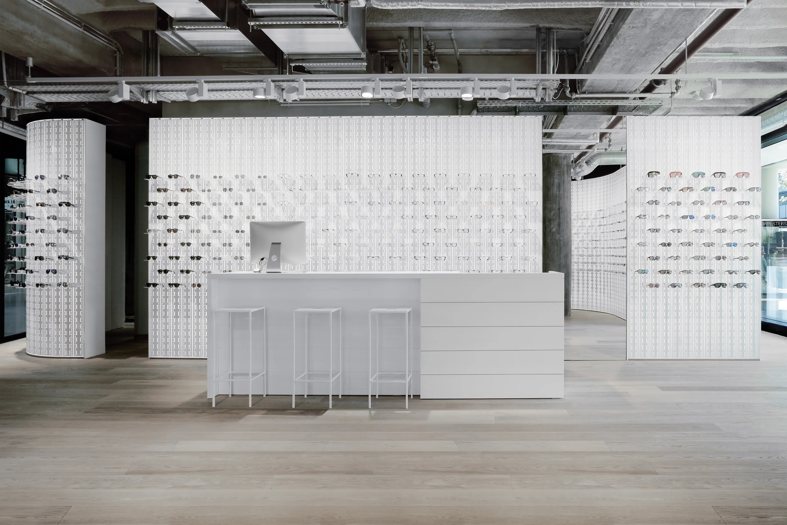 Minimalistisches Shopdesign - weißer Kassentresen vor einer weißen Produktpräsentationswand