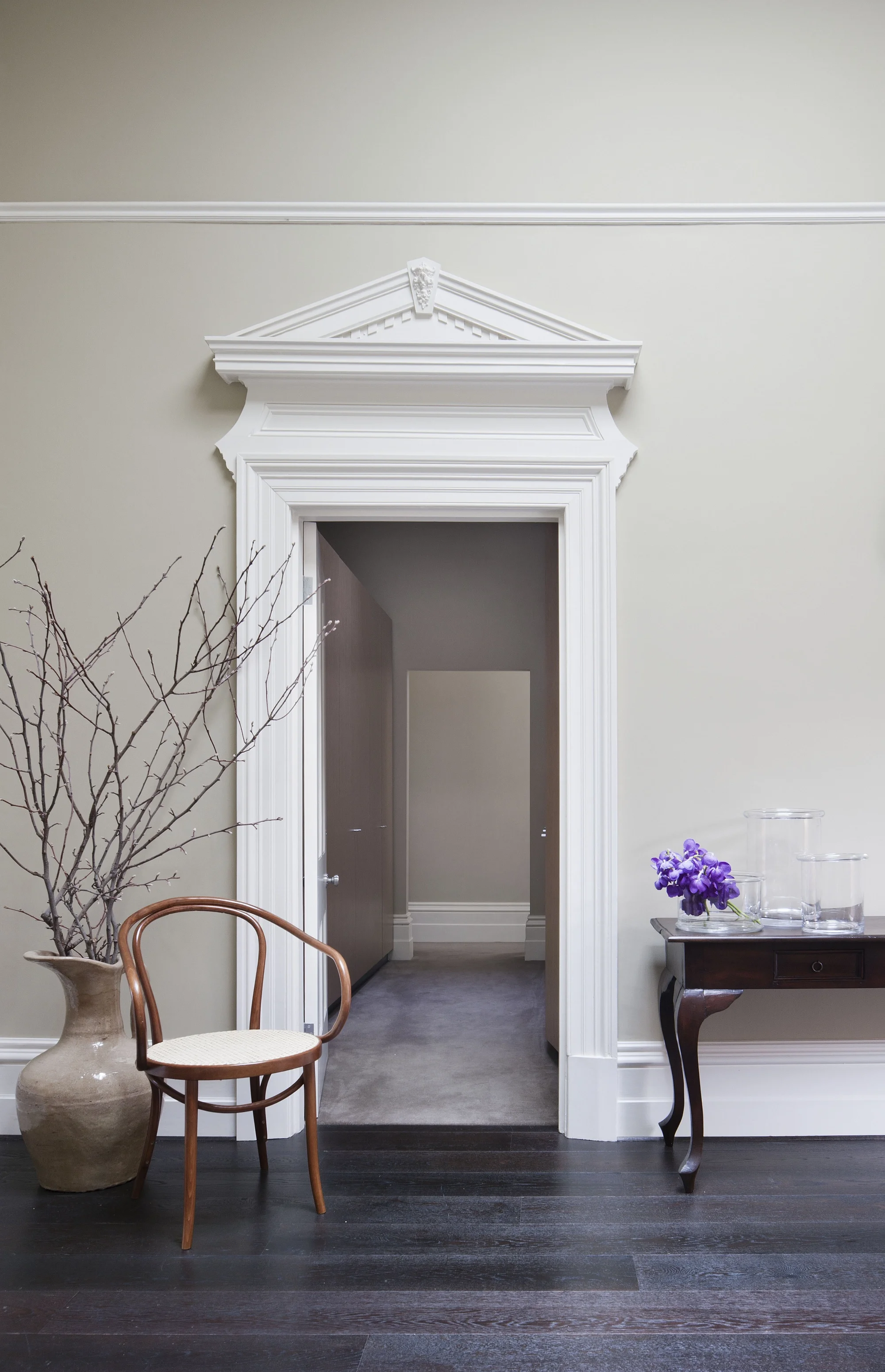 Prunkvoller Eingangsbereich mit klassischem Holzstuhl von Thonet und einer Konsole aus Holz.