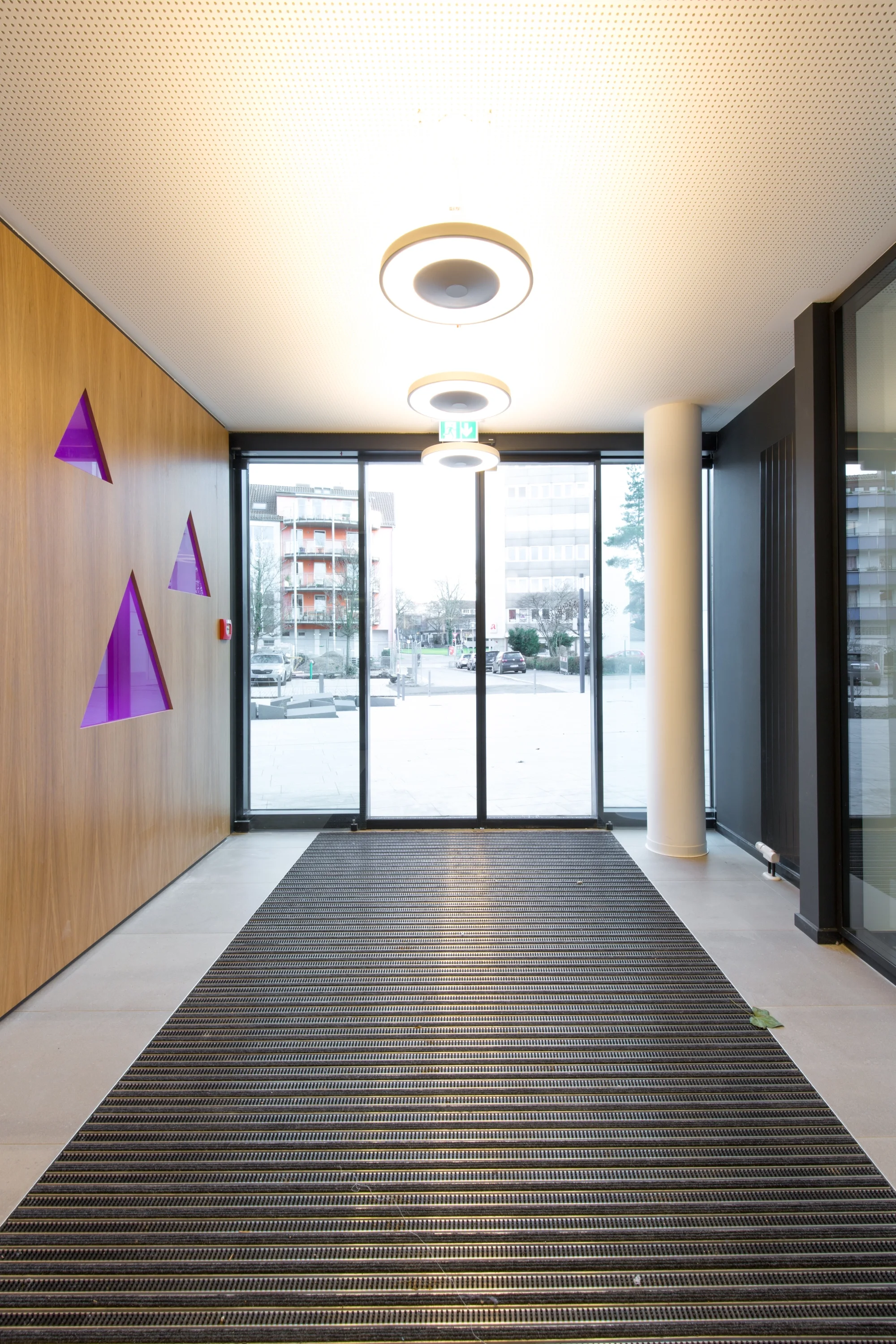 Eingangsbereich mit Logo in der CI-Farbe Pink auf einer Wand aus Holz.