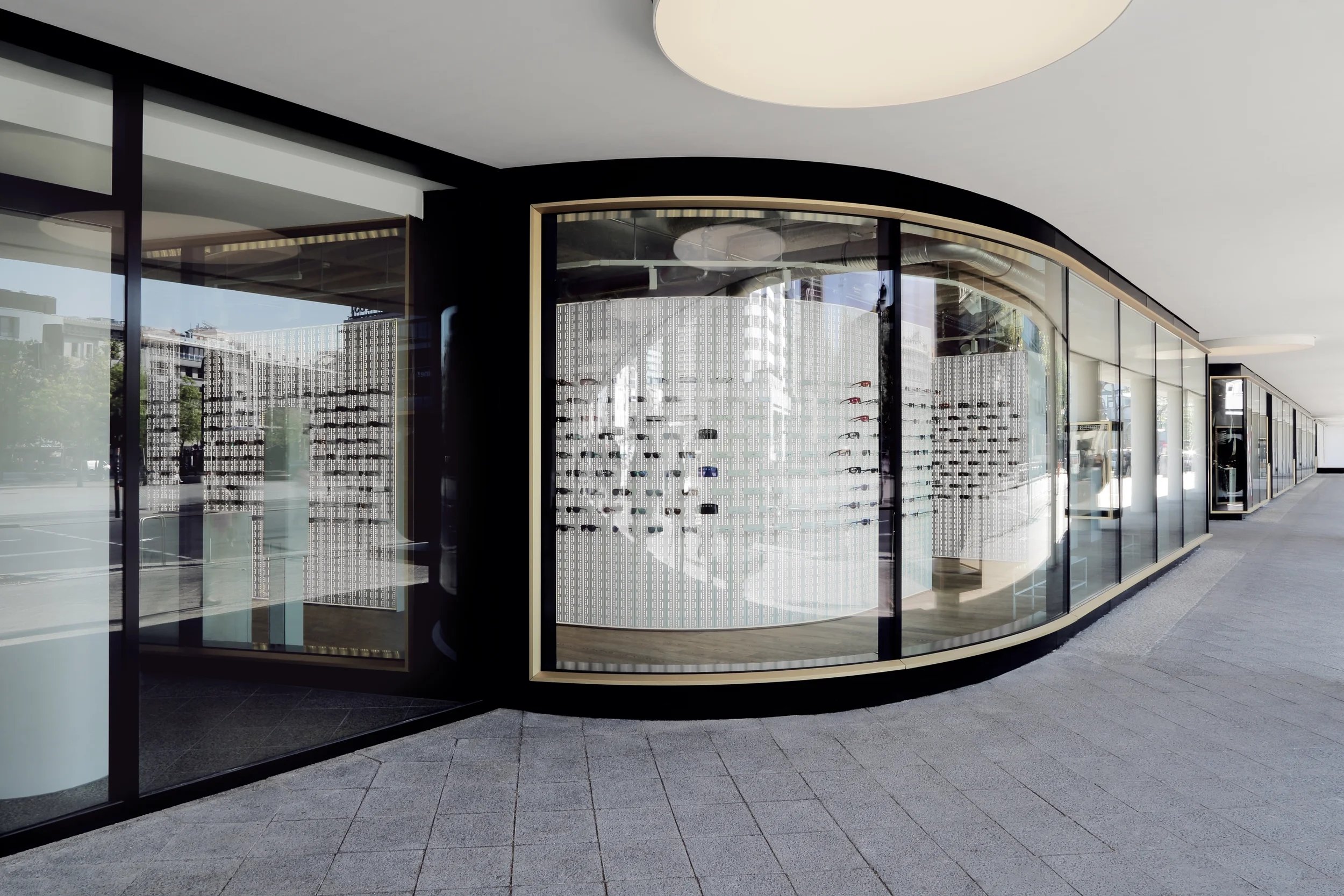 Perfekte Symbiose von Architektur und Innenarchitektur – Die Warenpräsentationswand folgt der runden Schaufensterfassade
