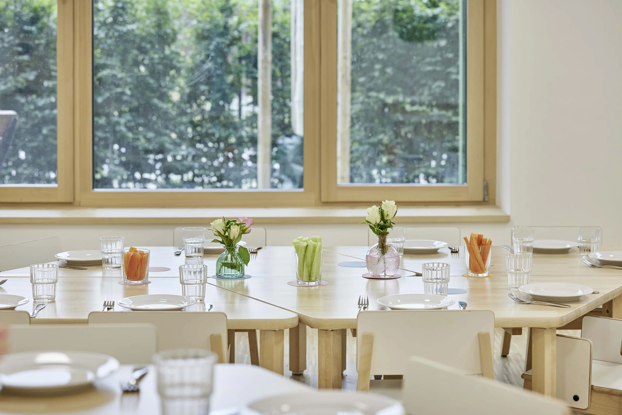 Speiseraum im Kindergarten mit Holztischen und Holzstühlen.