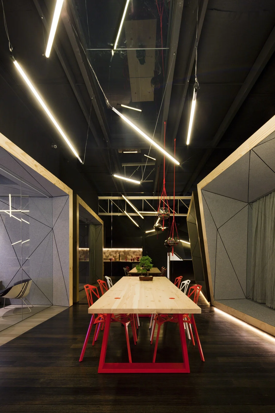 Meeting-Bereich in offenem Büro-Loft. Schwarze Wände und Decke, Holz-Pods und Akzente in der CI-Farbe Rot