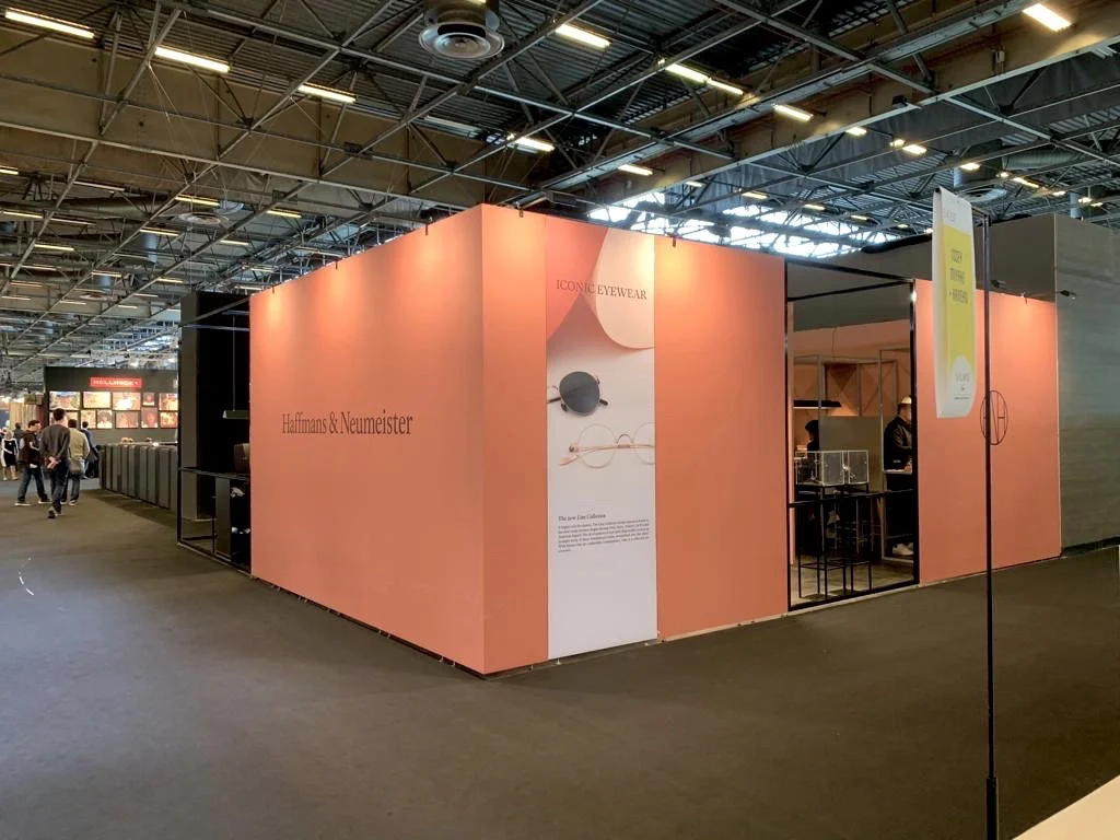 Aussenflächen des Messestands in warmen Rottönen mit schwarzen Logos.