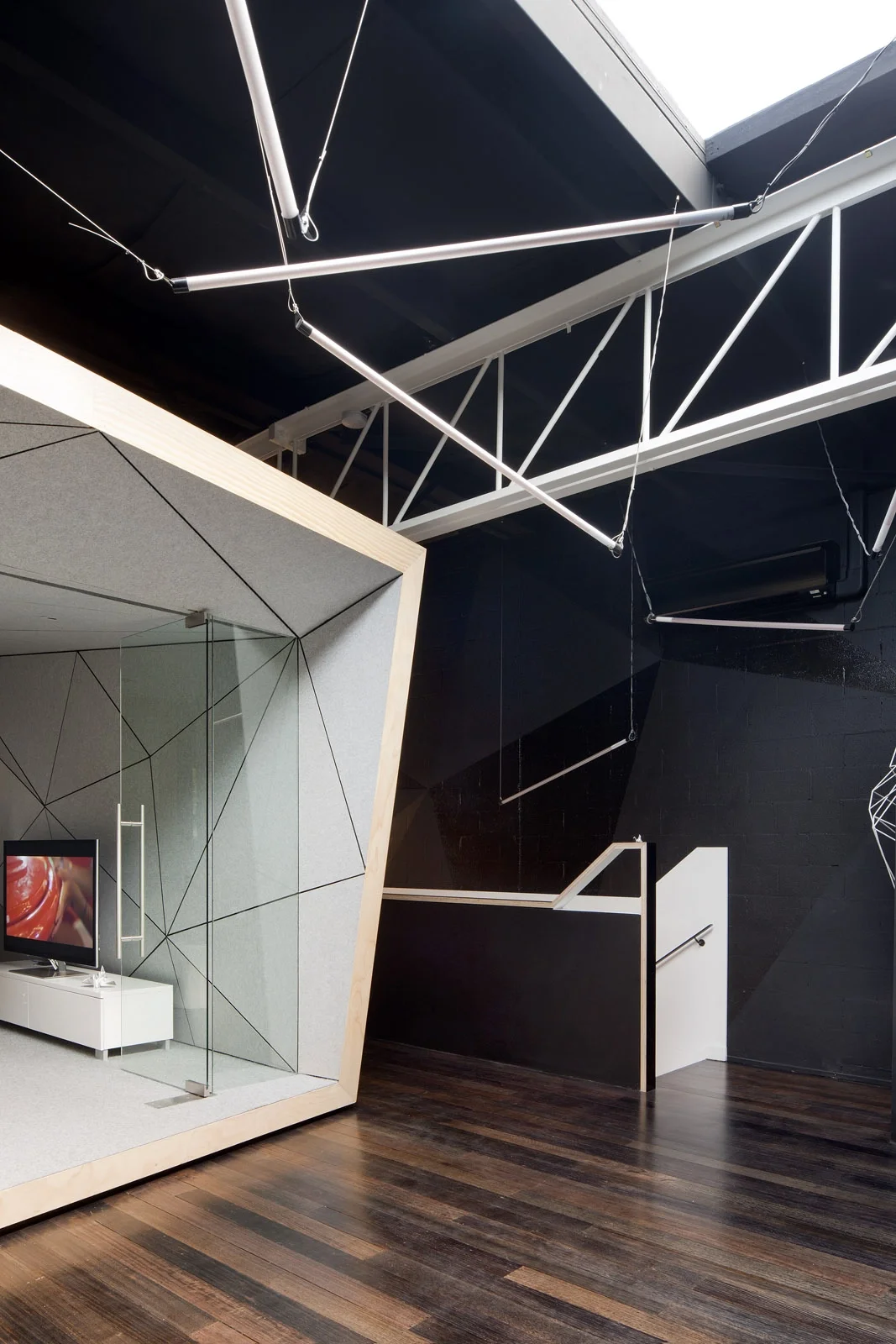 Co-Working Space mit innovativen, freistehenden Pods aus fragmentierten Holzflächen. Das Loft ist komplett schwarz und bietet einen dramatischen Hintergrund für das innovative Interior Design.