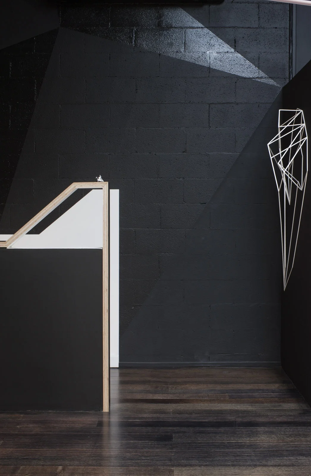 Innenraumplanung eines Büroeingangs mit einer weißen Treppe vor schwarzen Wänden und dunklem Holzboden.