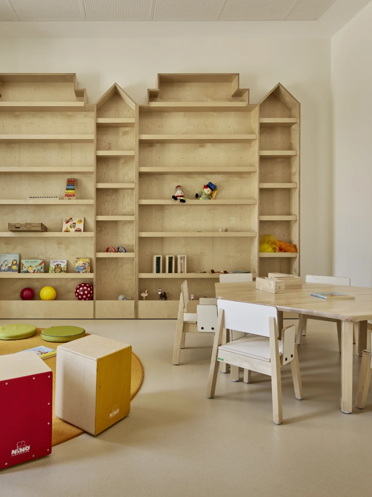 Maßgeschneiderte Holzregale in Häuserform aus Holz für einen Aufenthaltsraum einer Kindertagesstätte