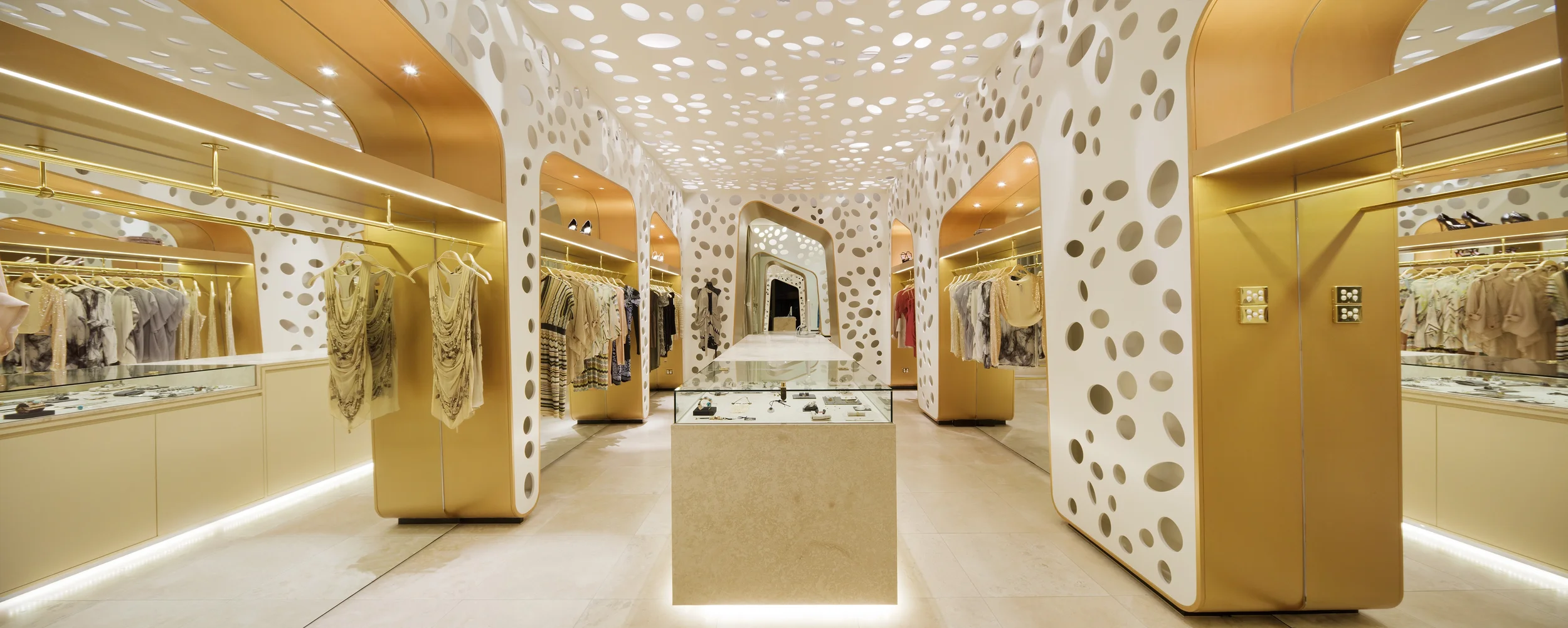 Panoramaansicht des Verkaufsraumes, im Zentrum der Verkaufstresen aus Naturstein und zu den Seiten die verspiegelten Wandnischen, die zur Warenpräsentation dienen.