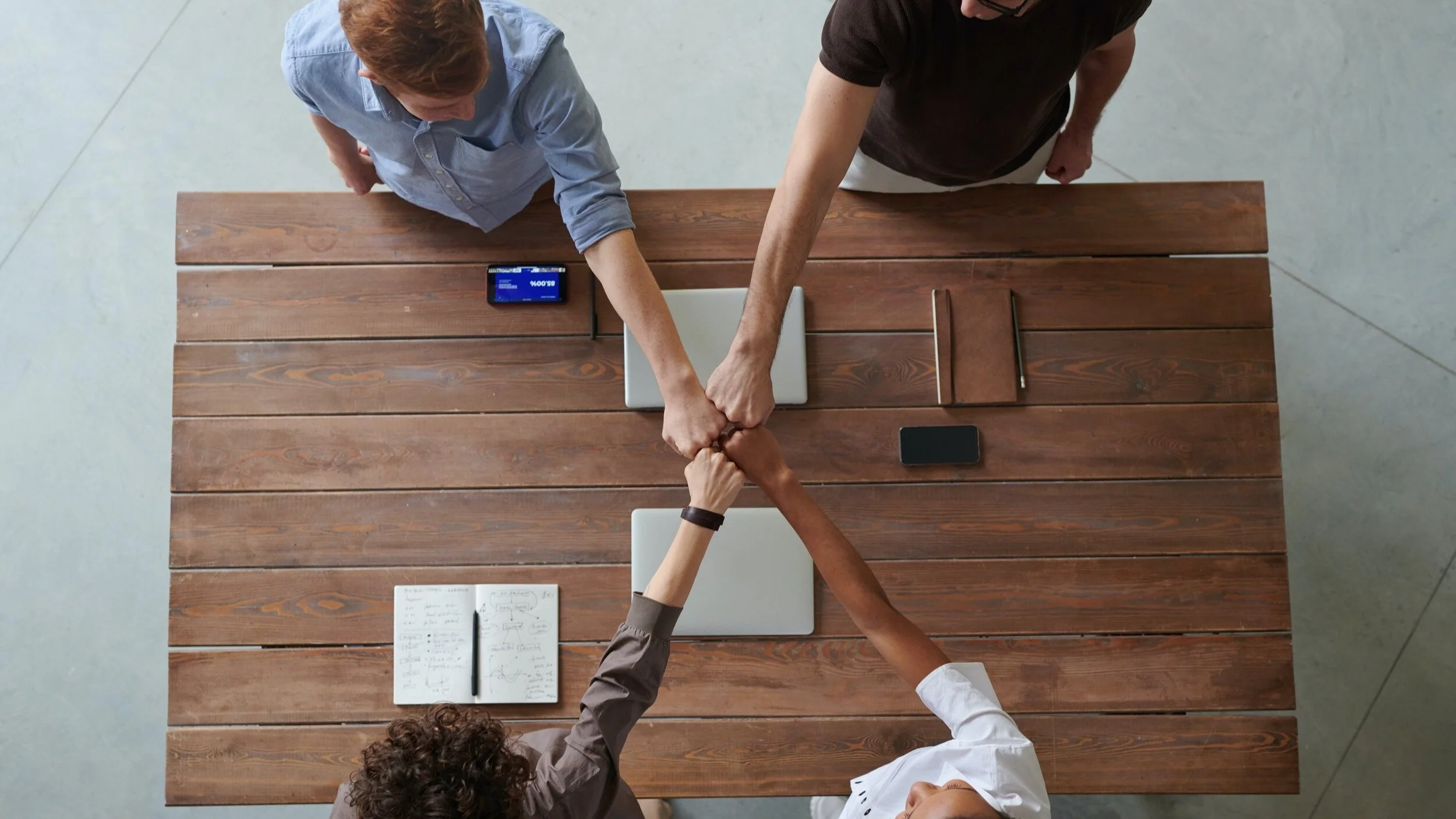 group of people doing fist bumps around a table