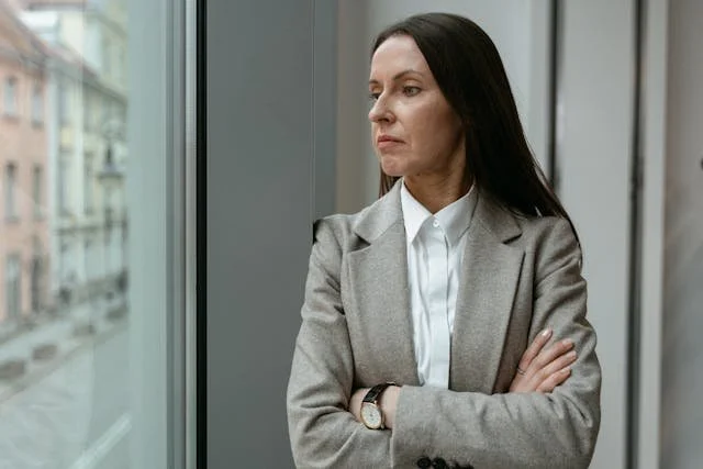 woman looking out of window arms crossed