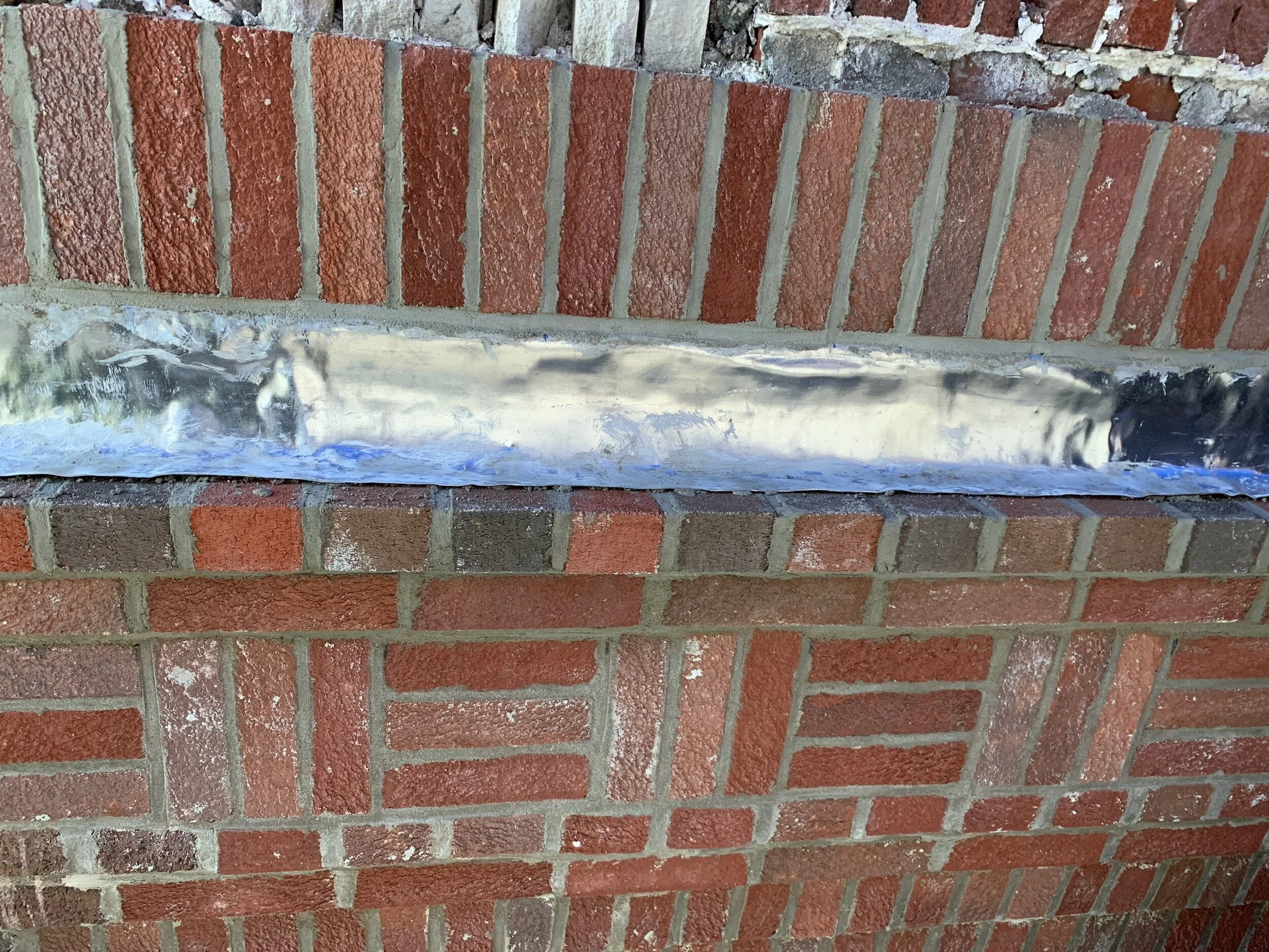 Brick wall with metal flashing and cement repair.
