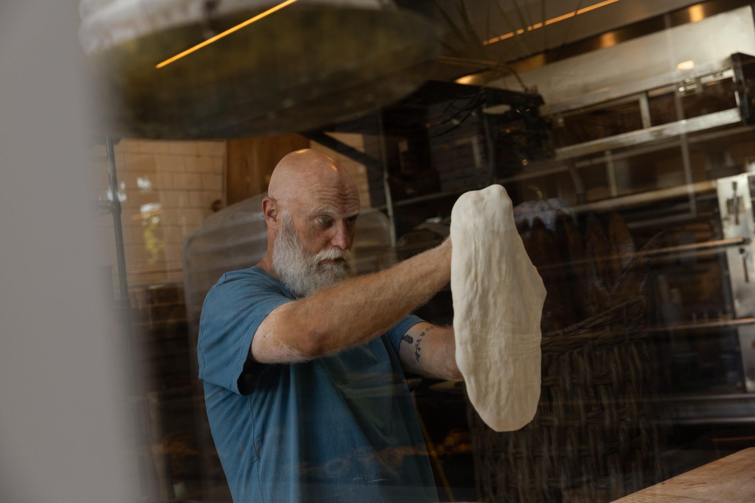 Chef Fede stretching dough by hand in Bianca’s kitchen in Culver City, highlighting traditional bread making.