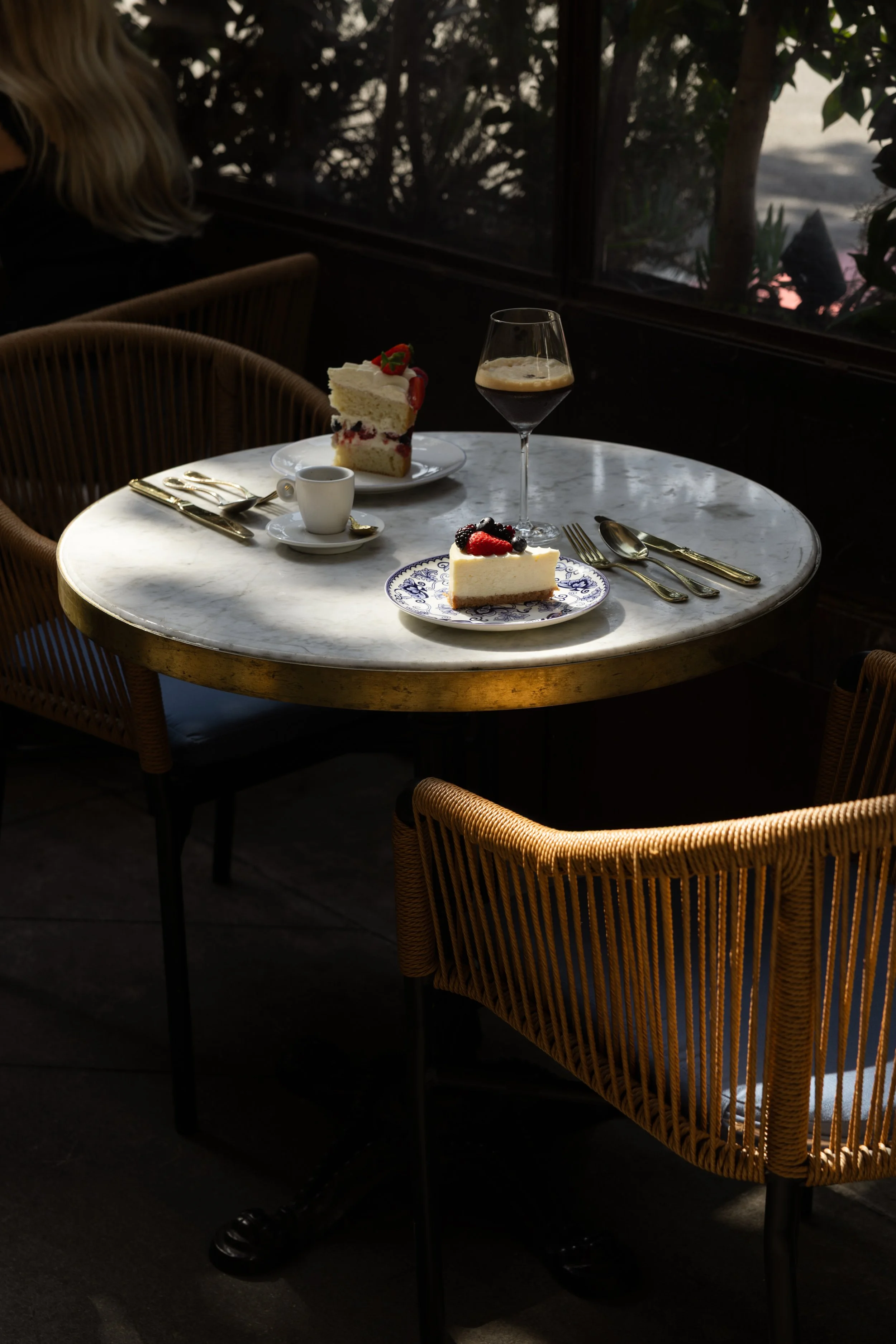 Set dining table inside Bianca restaurant in Culver City, featuring a marble tabletop and woven chairs.