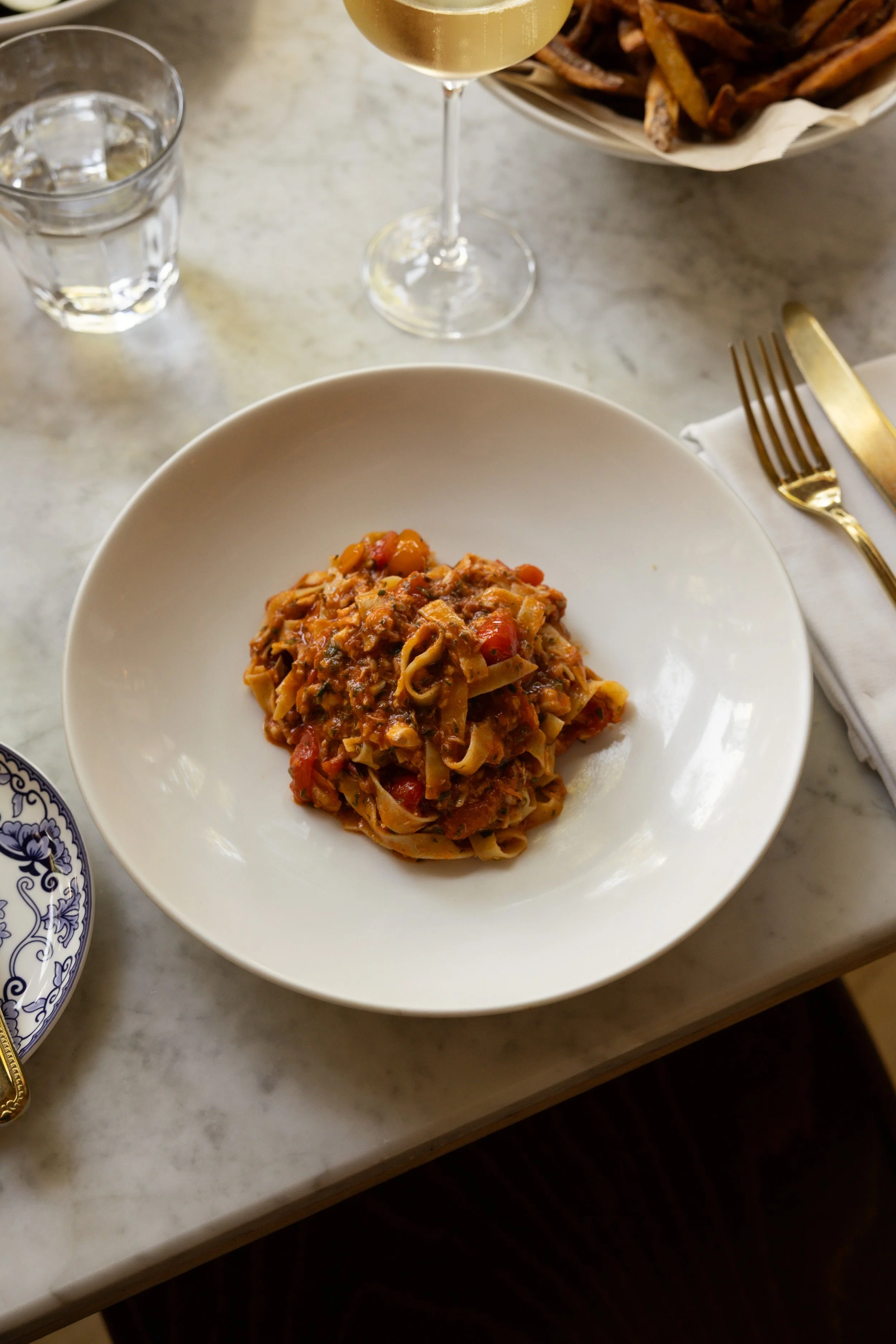 Seasonal pasta dish served at Bianca restaurant in Culver City, plated on a white dish at a marble table.
