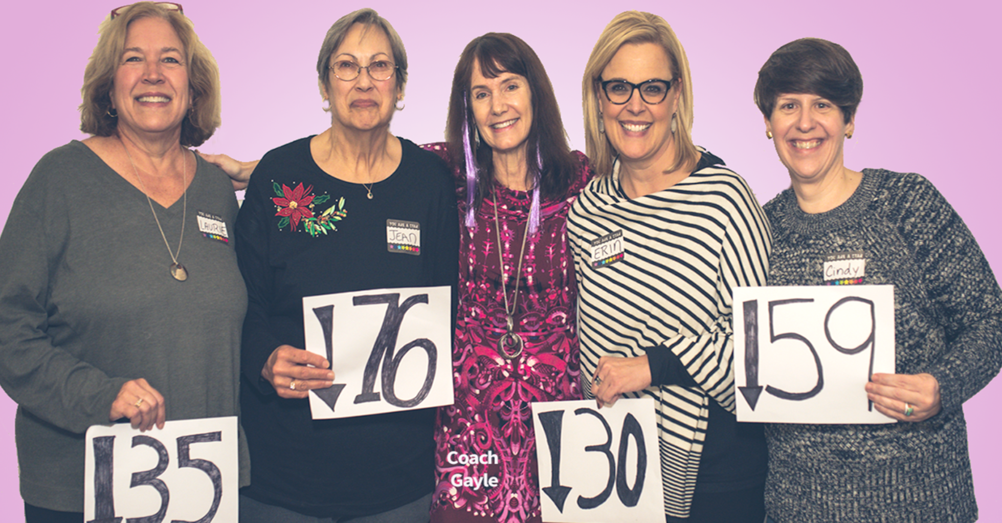 Coach Gayle stands surrounded by four of her clients. They are celebrating their weight loss and fitness goals.