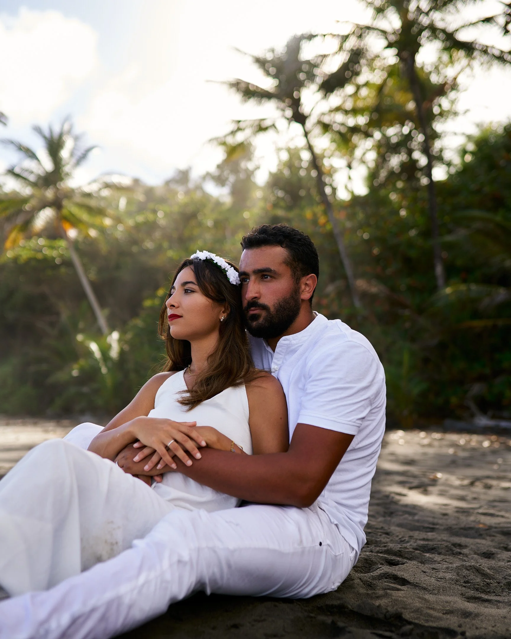 Deux mariés assis sur une plage au sable noir.