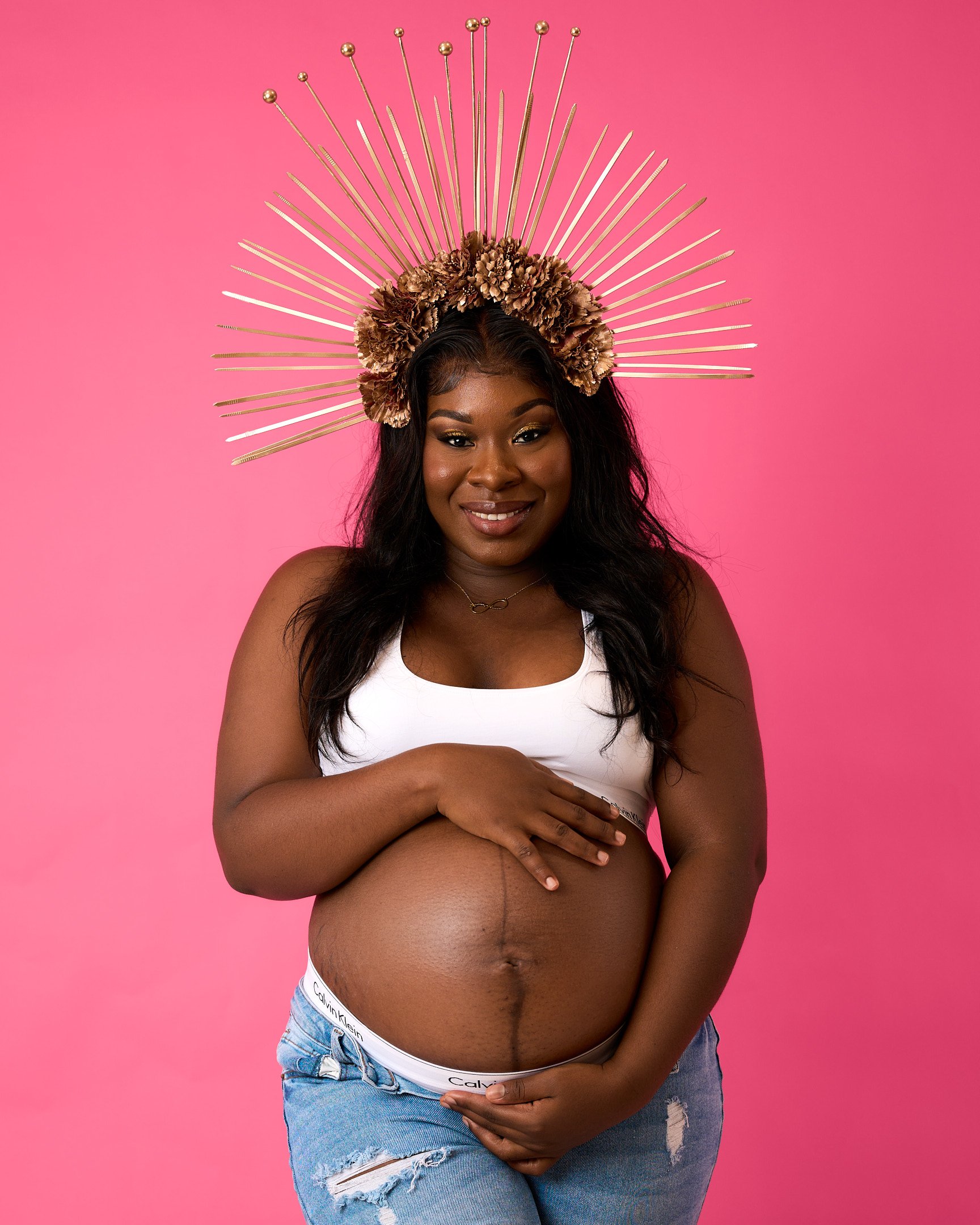 Une photo de grossesse en studio avec un fond rose.