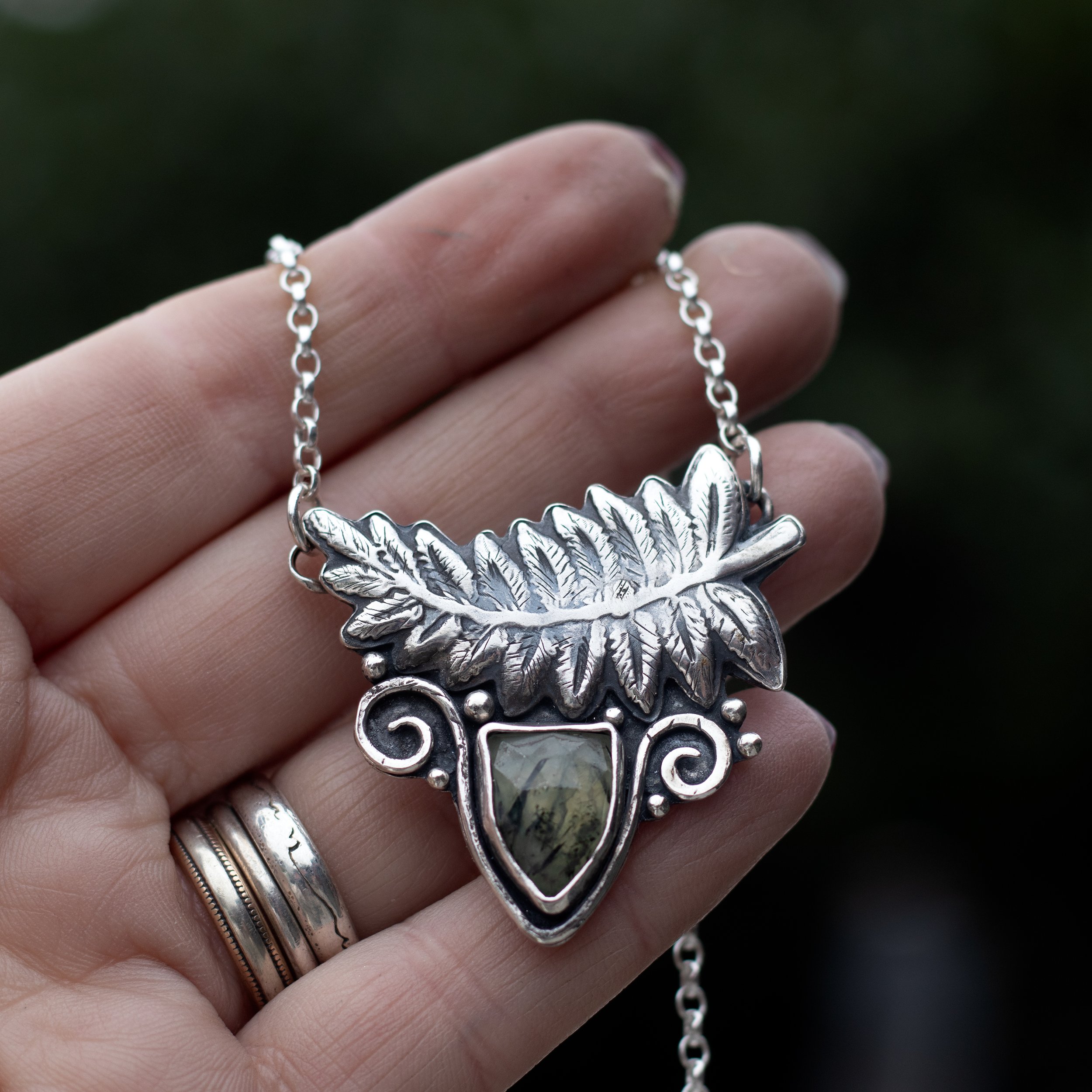 A detailed silver pressed fern with a beautifully spring like prehnite set amongst silver - my beautiful ode to Spring. Necklace designed and made by Gemheaven Jewellery and displayed on a hand.