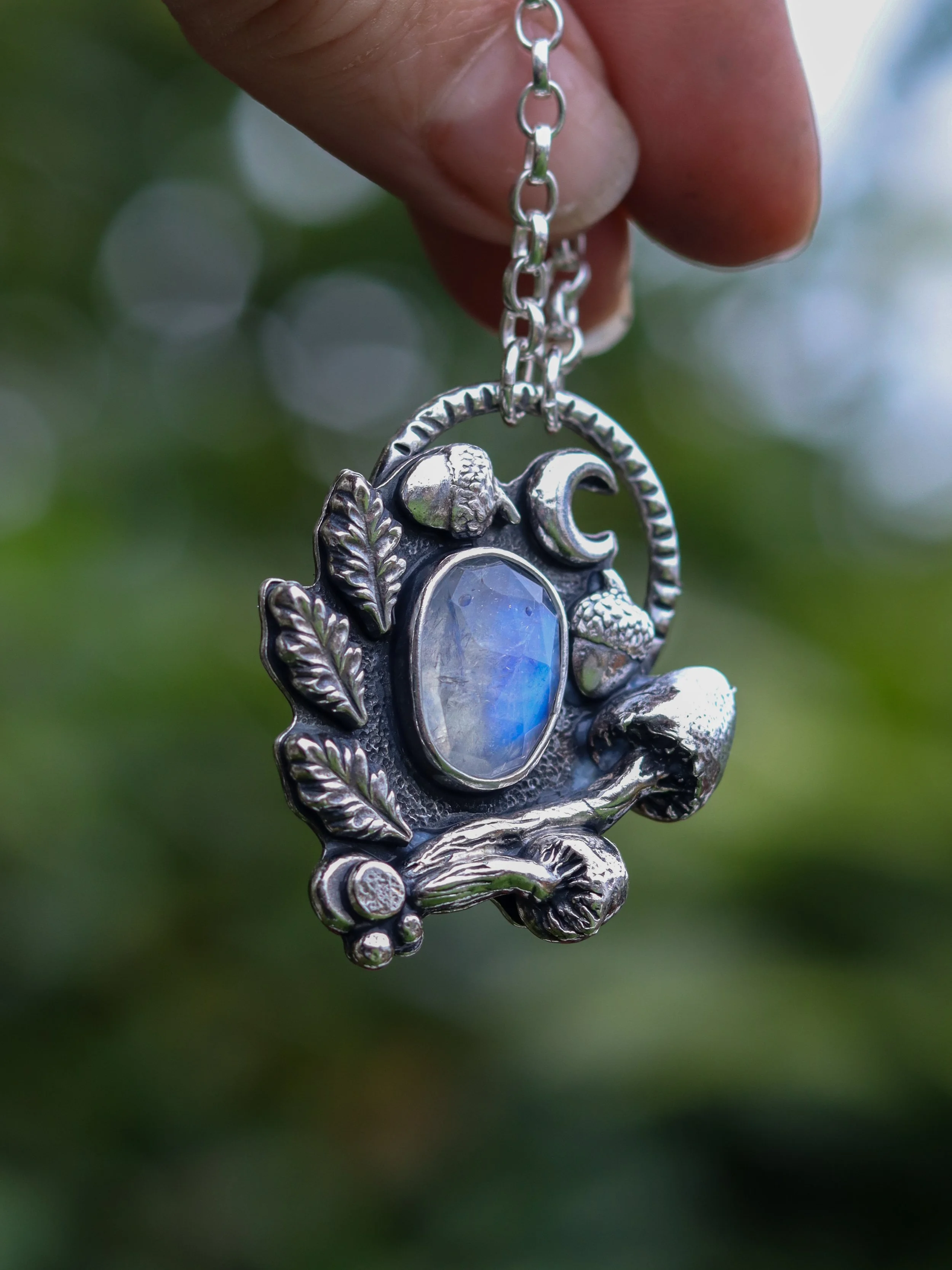 A Talisman of Moonlight and Forest Magic, Handcrafted in sterling silver, rainbow moonstone, encircled by oak leaves, acorns and mushrooms.