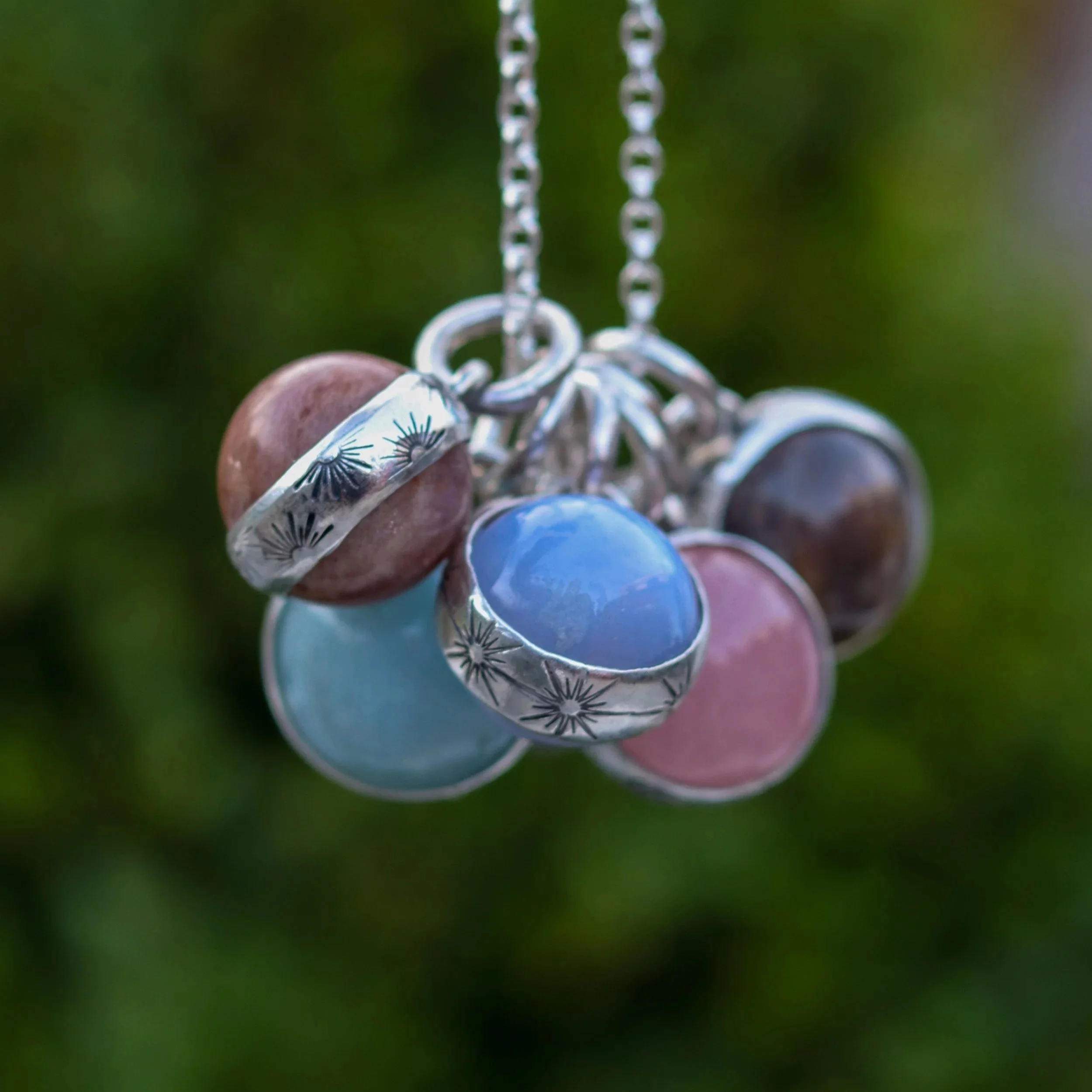 Selection of mini crystal balls in a variety of gems with silver ring around them, featuring celestial designs. by Gemheaven Jewellery