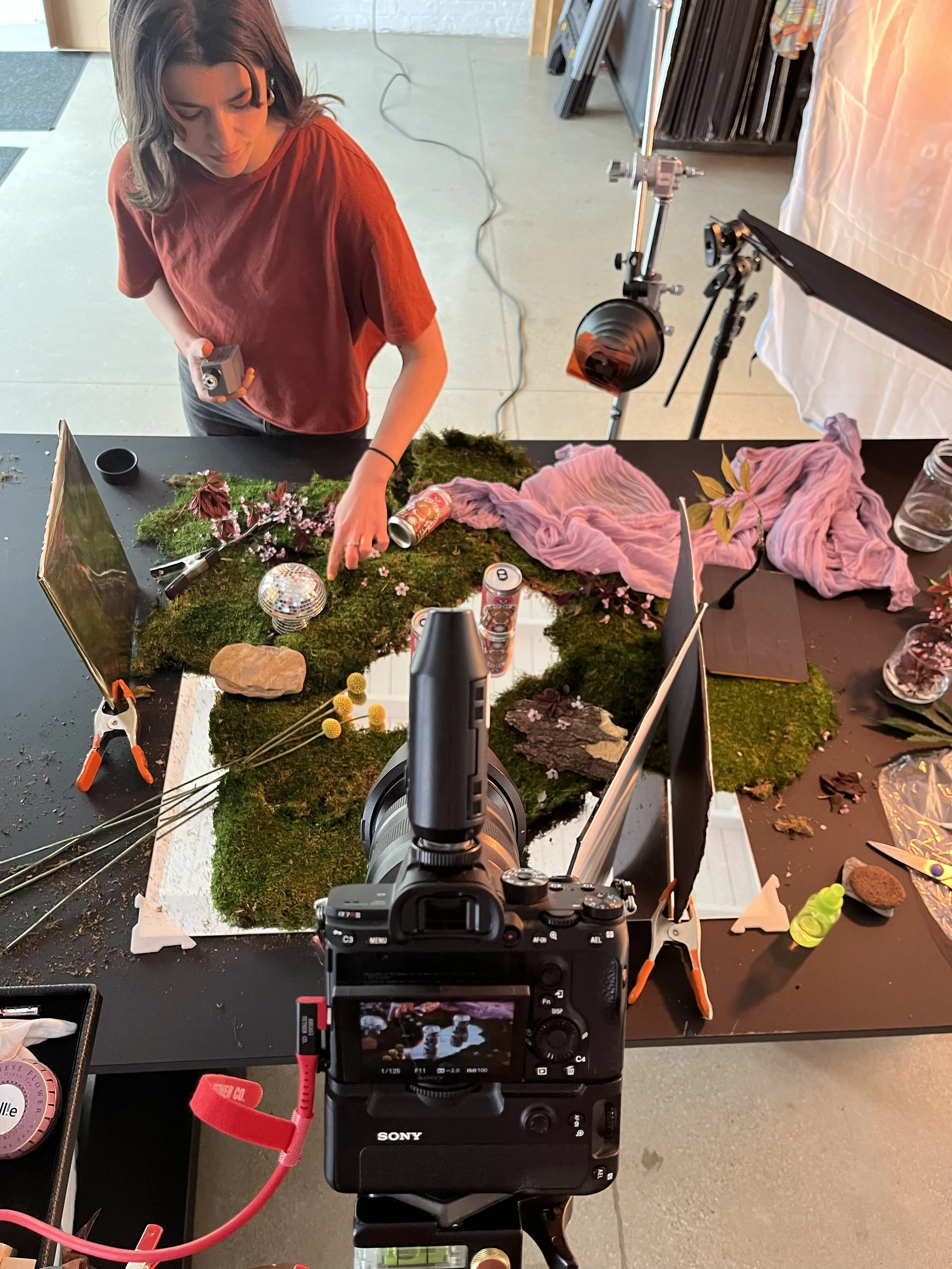A female prop stylist, styling a set made of moss, a mirror and natural elements