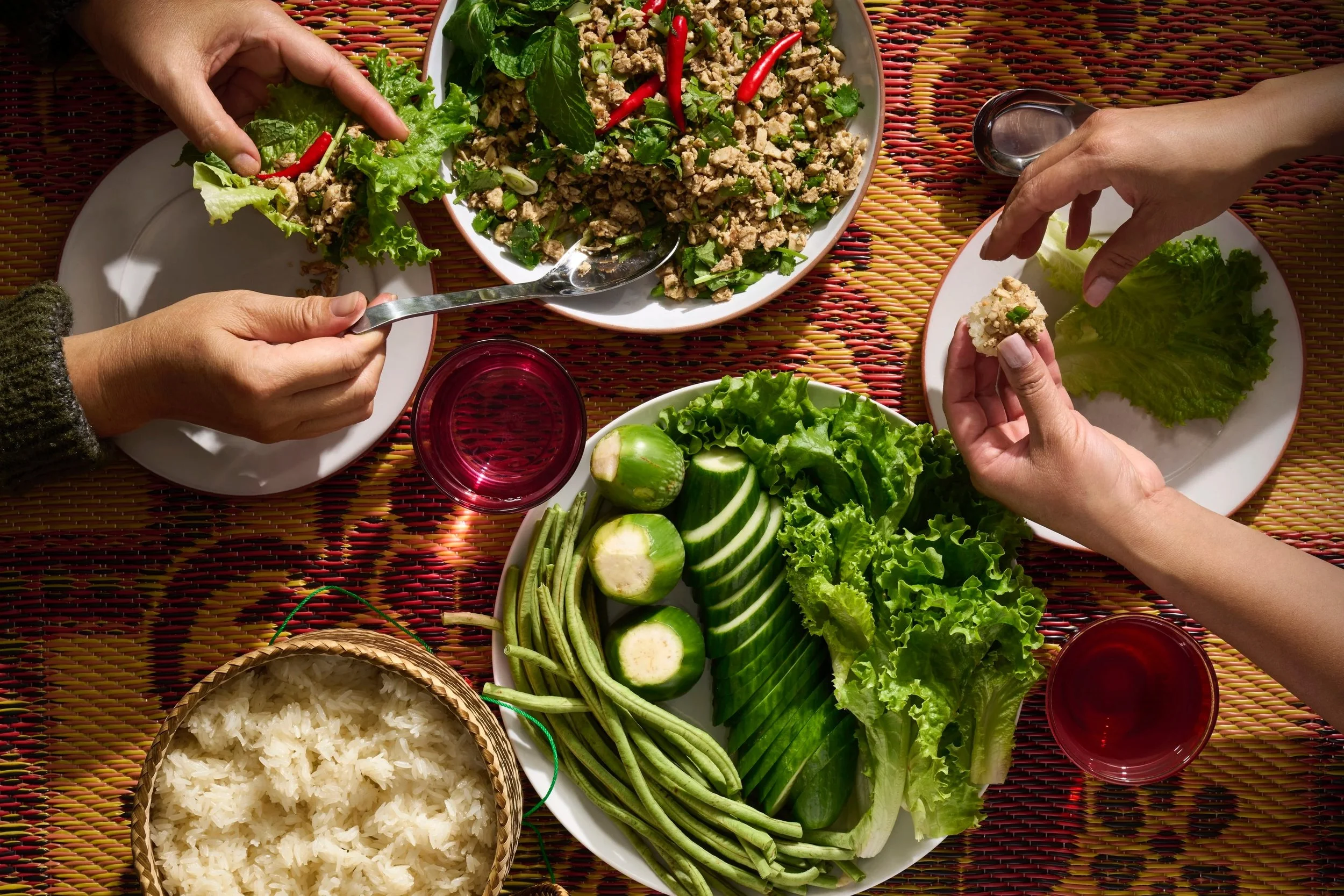 overhead shot of a tabletop, hands coming in from either side sharing food