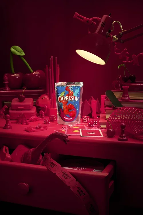Capri Sun juice on  red desk with nostalgic 90's toys with a glowing lamp
