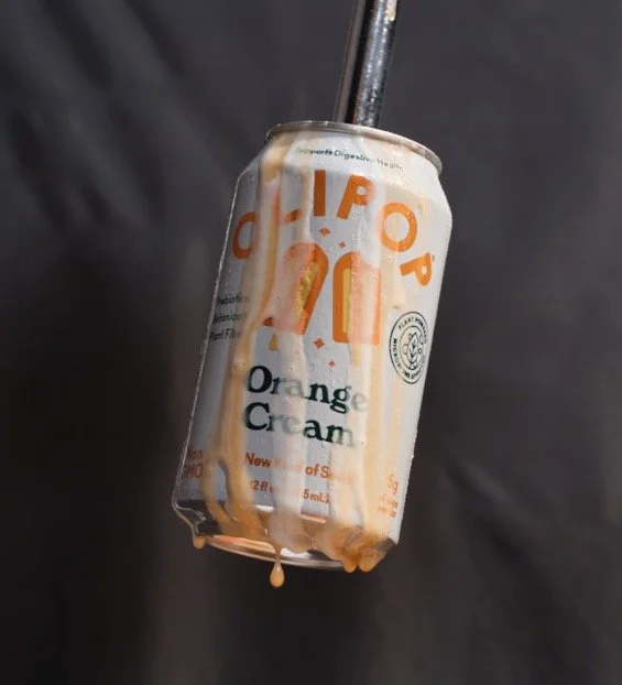 Can of orange cream soda with orange creamsicle drips drizzled over the can.