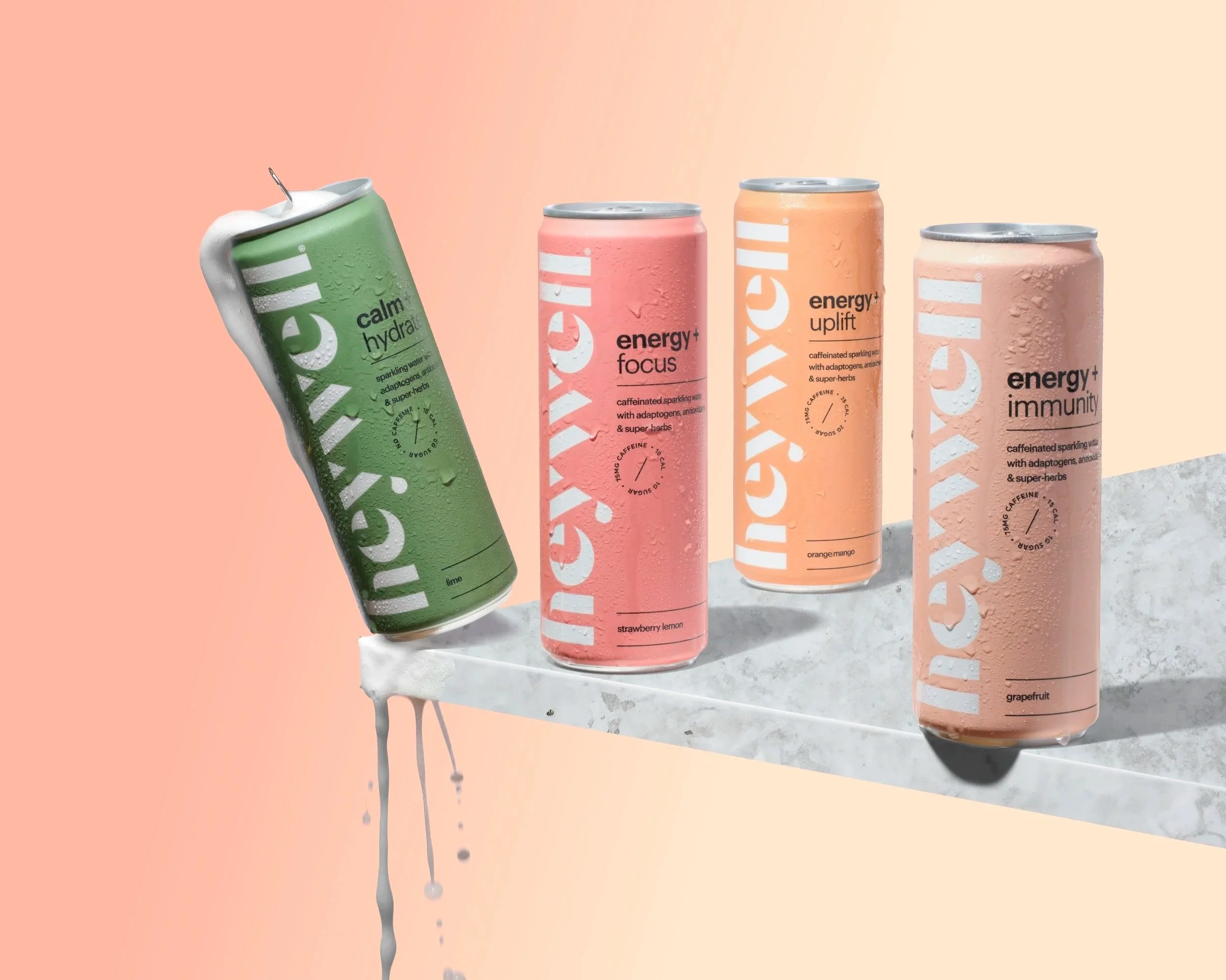 Cans of adaptogen sparkling beverage.  Green, pink, salmon and orange sitting on a marble surface.  The green can is slightly tipped off the edge and the liquid on the can is foaming and splashing.