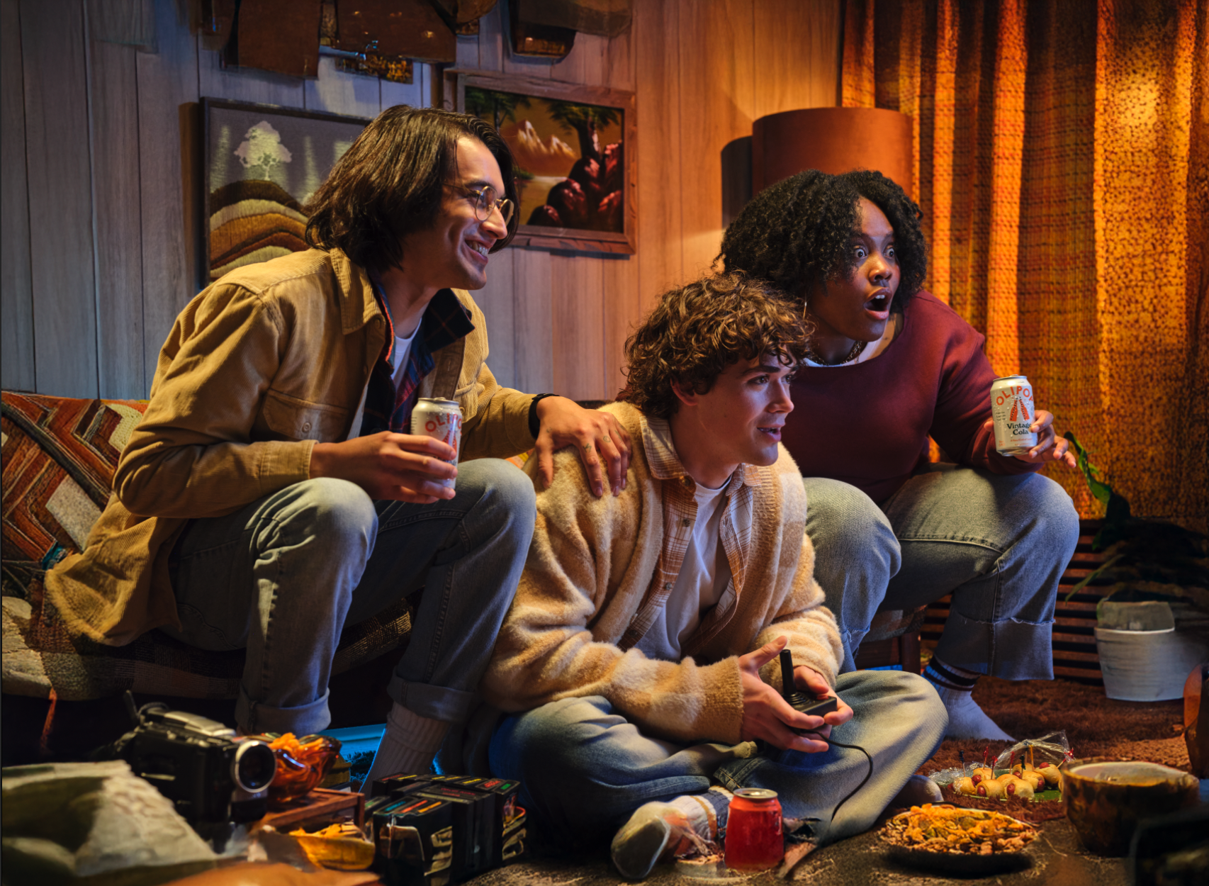 3 people sitting on a couch playing video games looking at the tv with anticipation