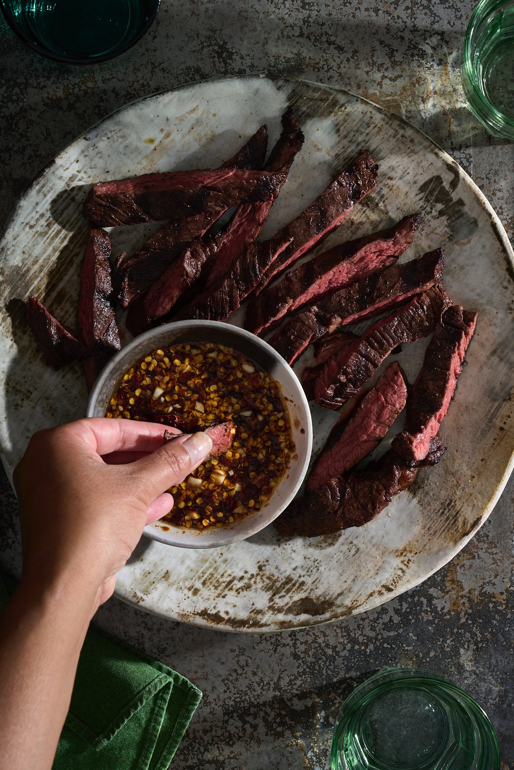 Hand holding a piece of meat dipping it into sauce.