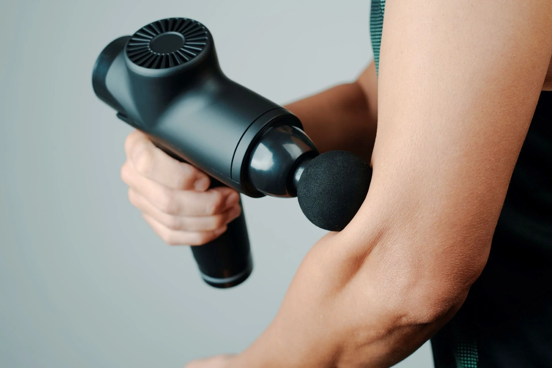 Massage Gun Benefits: What You Need To Know - Man+using+a+massage+gun+on+his+arm