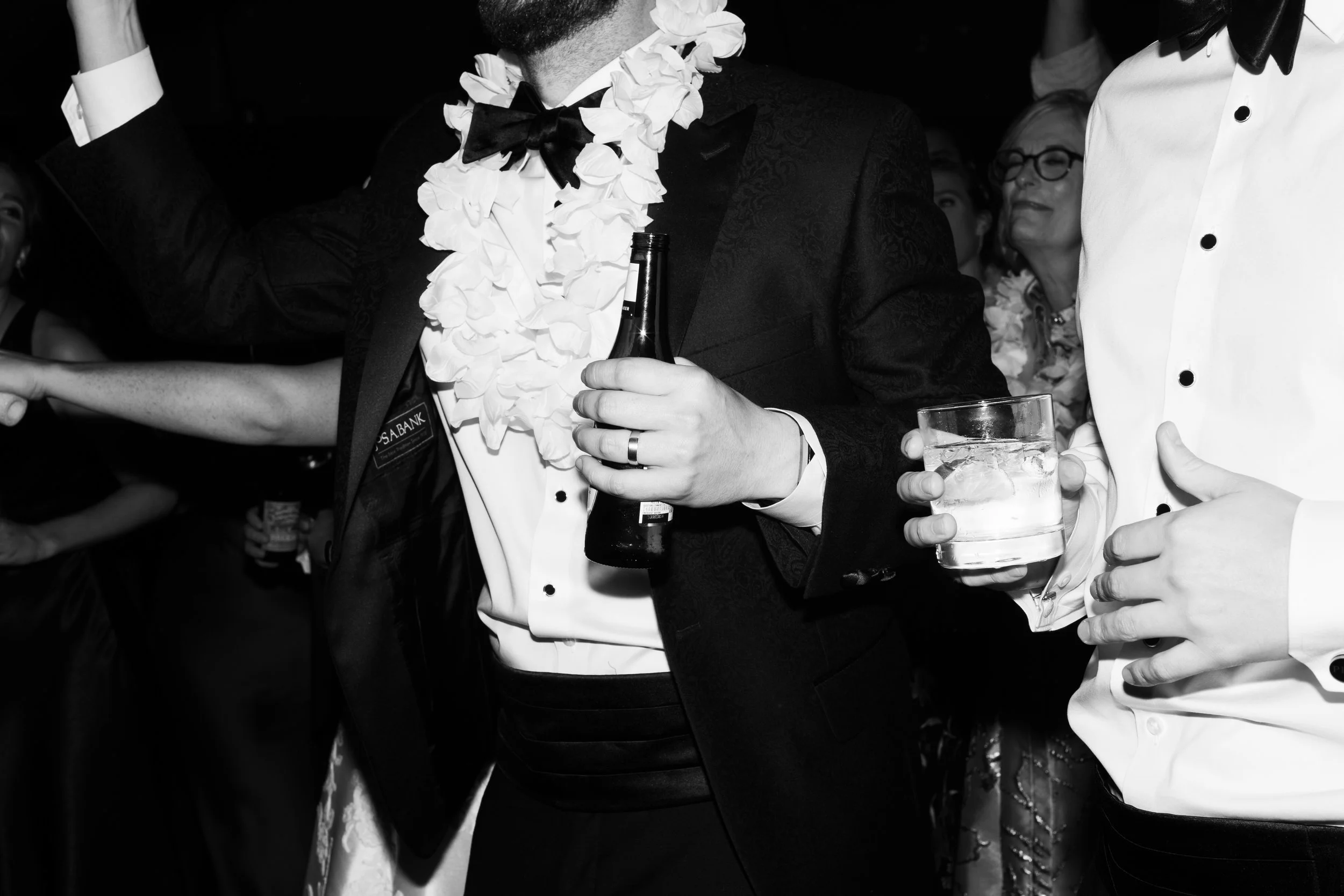 People dressed in formal tuxedos celebrating with drinks at a party.