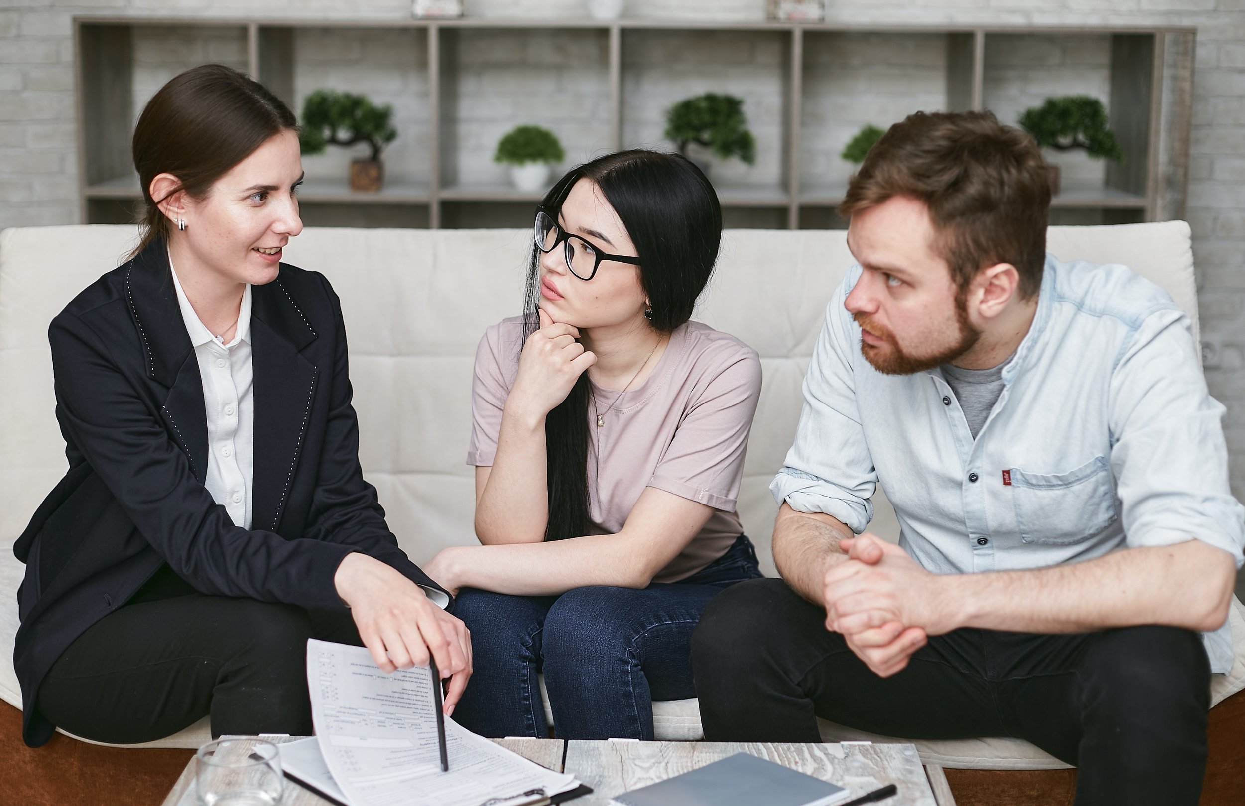 Three people reviewing documents together on a sofa