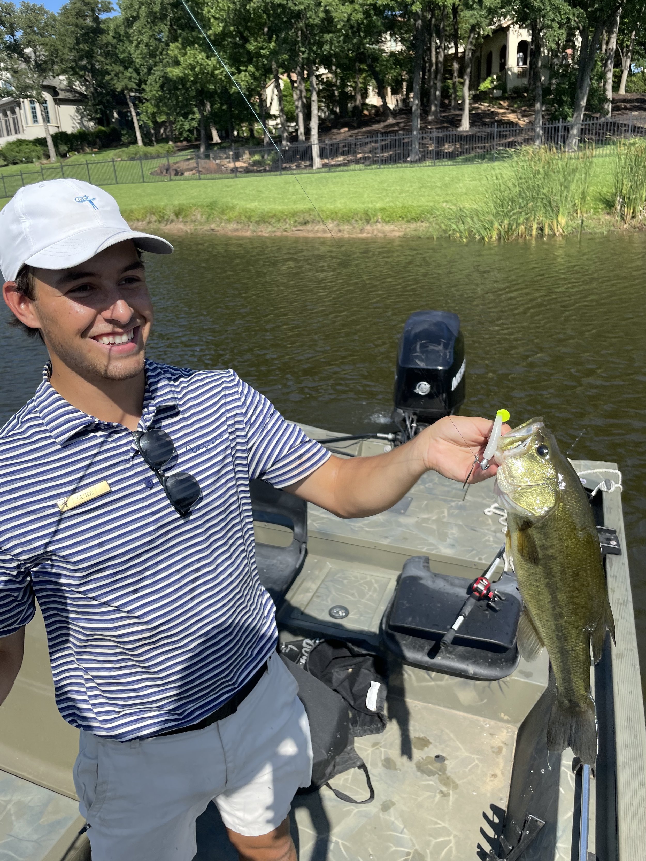 Man holding a fish on a boat by a lake