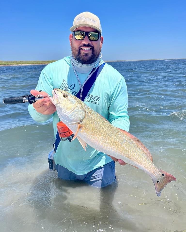 Man holding a large fish in shallow ocean water