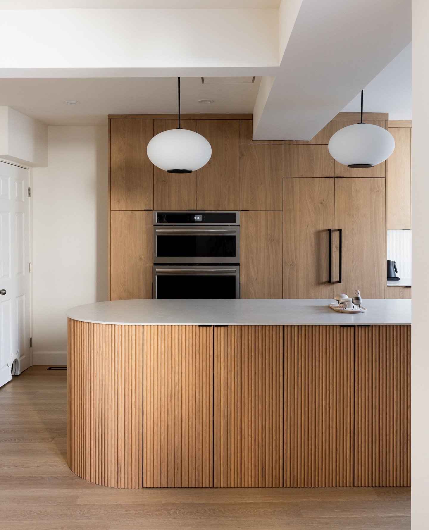 Inspired by Japandi design, this renovation aimed to create a calm, connected space by opening the kitchen to the surrounding rooms and unifying the main floor with continuous flooring. Complementary red oak details bring warmth and cohesion, while n