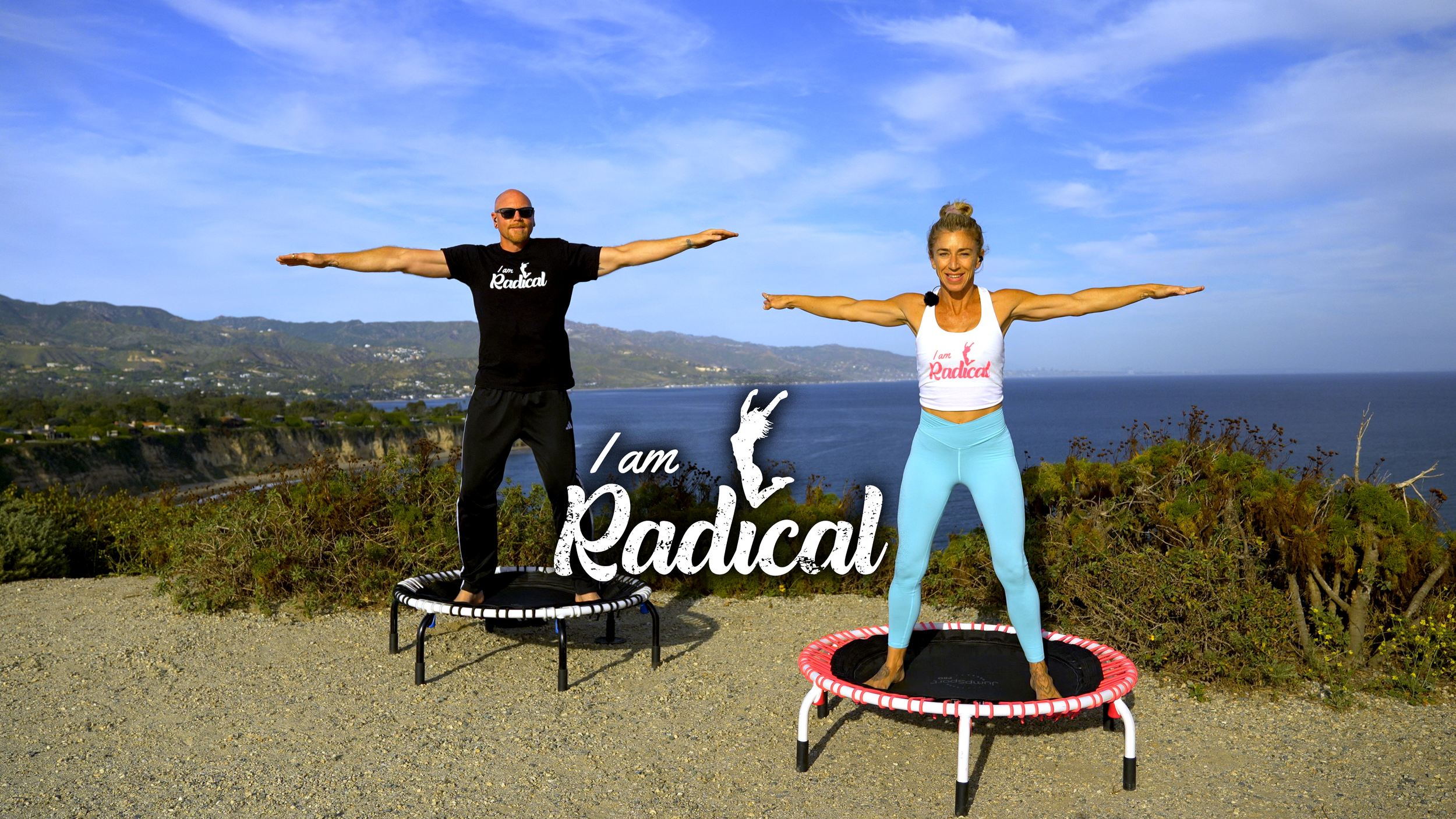 A man and woman standing on mini trampolines outdoors near a coastal landscape with mountains and blue sky, both extending their arms sideways. The man is wearing sunglasses and a black shirt that says 'I am Radical.' The woman is in a white tank top with the same phrase and light blue leggings. The image includes the words 'I am Radical' with a sparking figure in the background.