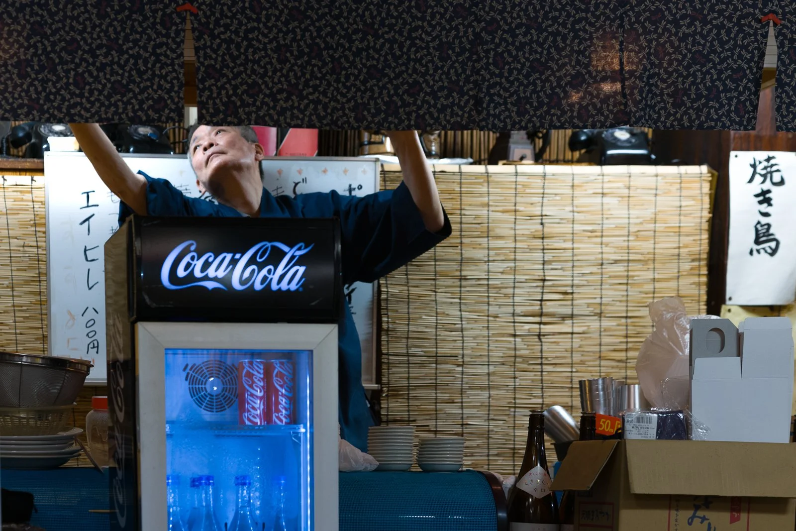 The owner of a local gyoza restaurant working behind the counter, preparing the space before service in a long-established izakaya in Utsunomiya.