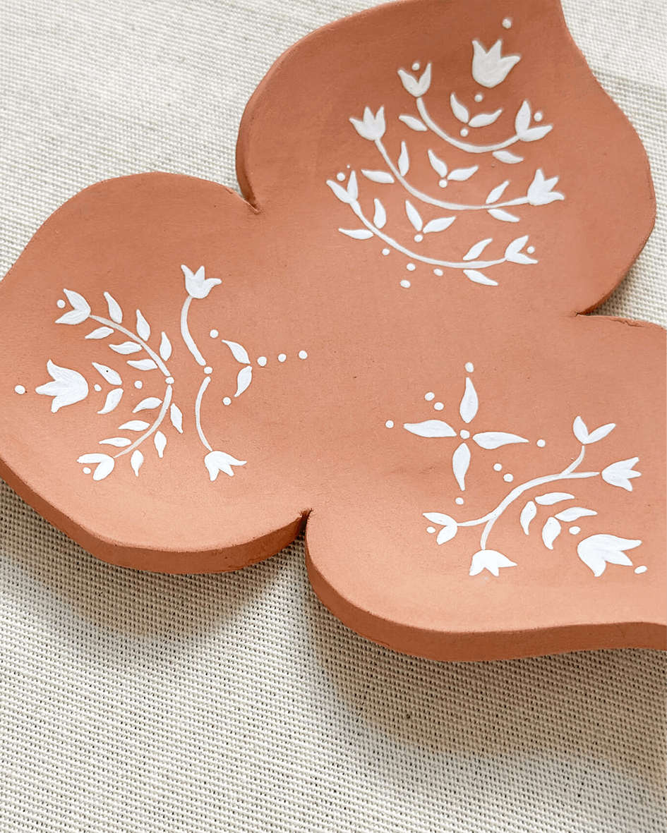 Detail Of A Handmade Collection of Terracotta Clay Curios Hand Painted With White Underglaze Pattern.png