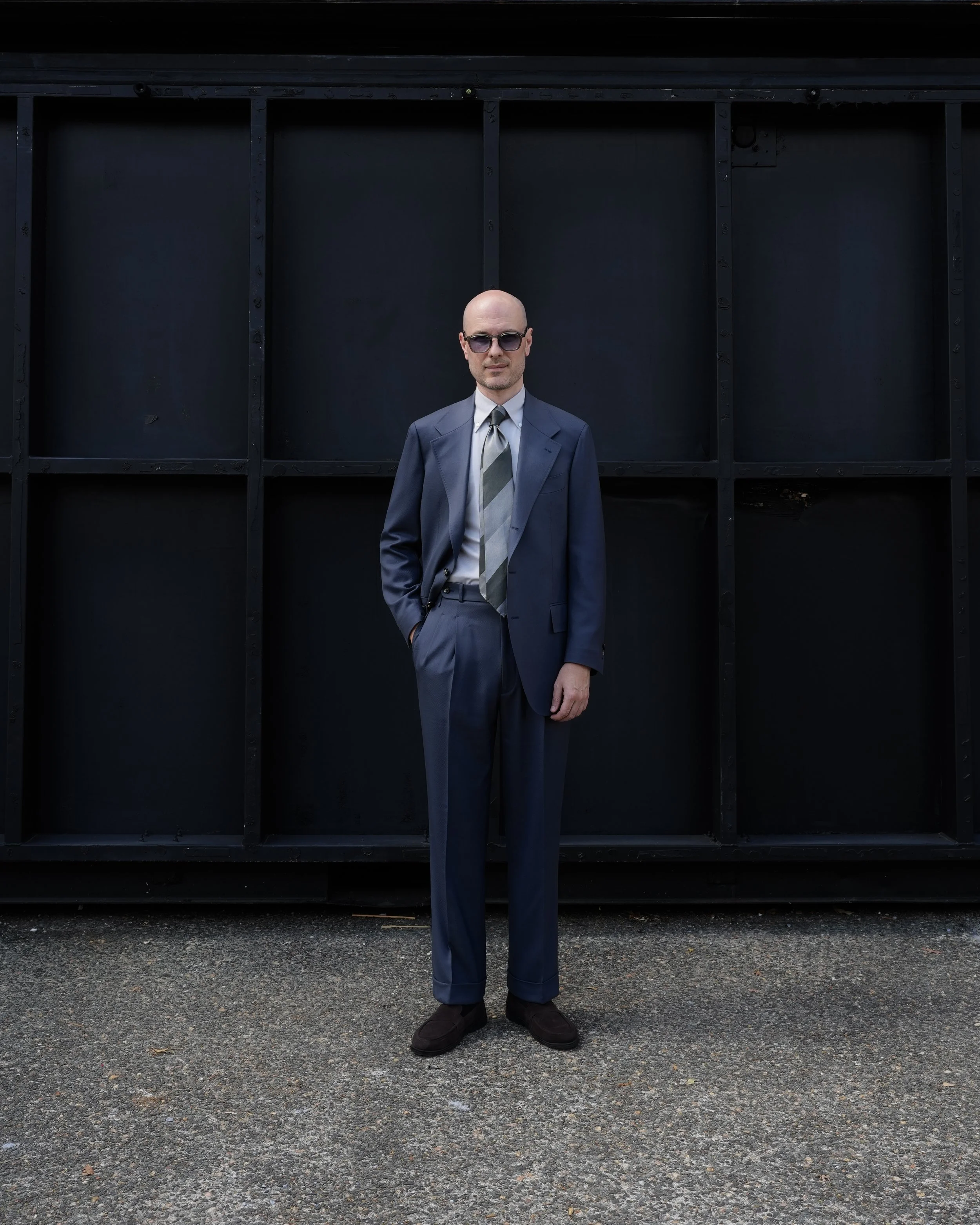 Aleksandar Stately Made-to-Measure specialist in a blue suit, light gray Aleksandar Stately shirt, and striped Aleksandar Stately tie standing outdoors in Brisbane.
