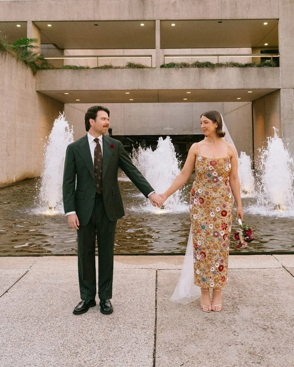 A man wearing a Aleksandar Stately custom tailored made to measure olive green suit and holding hands in front of a fountain at Brisbane Museum.