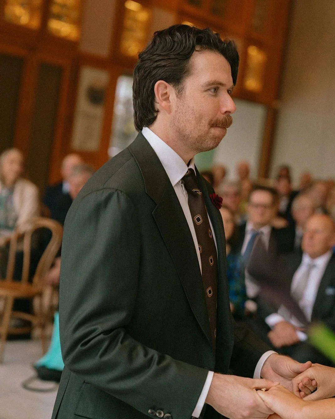 A man wearing a Aleksandar Stately custom tailored made to measure olive green suit during a wedding ceremony at QPAC Brisbane.