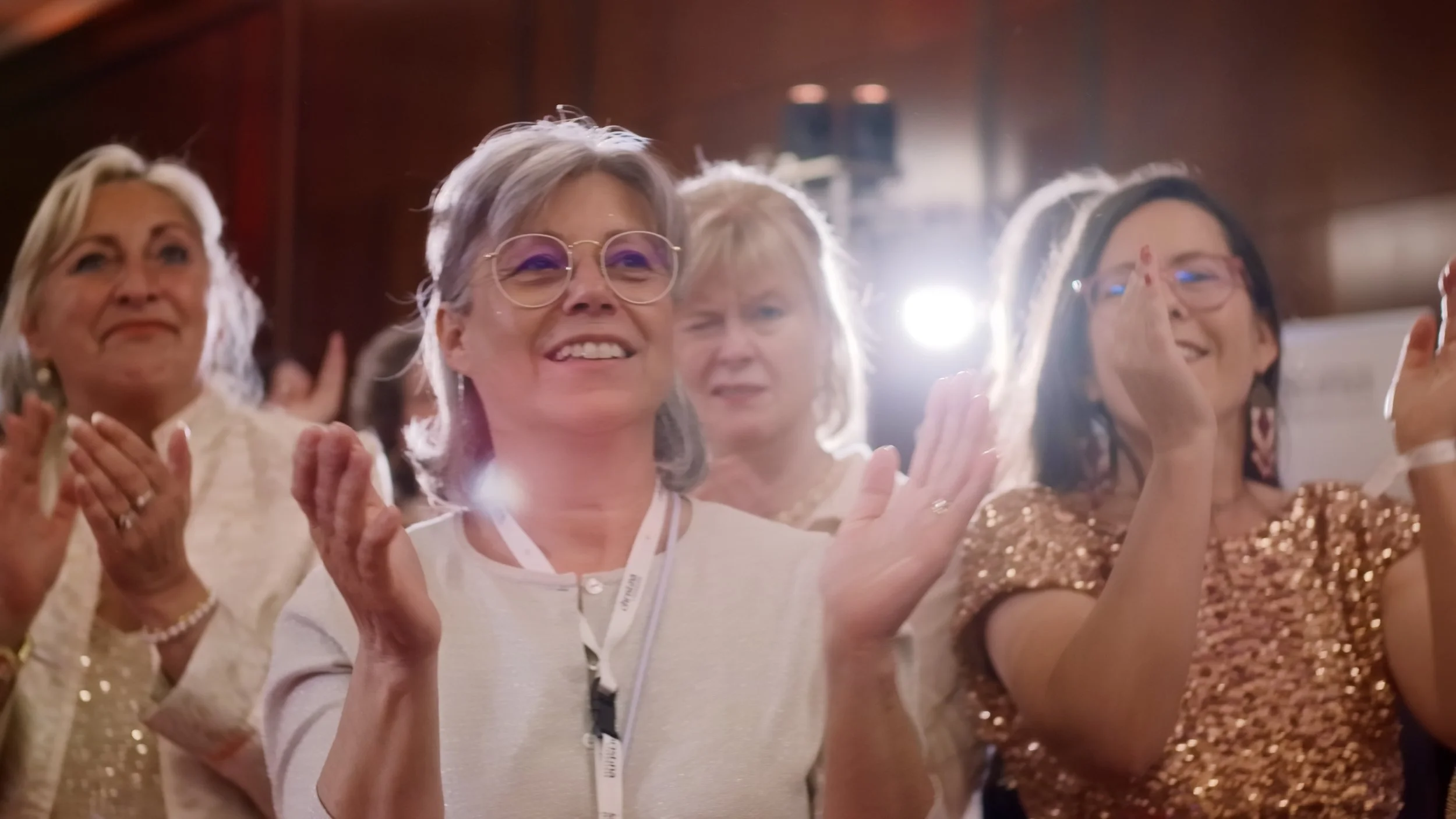 Eine Gruppe von Frauen im festlichen Ambiente, die applaudieren und lächeln.