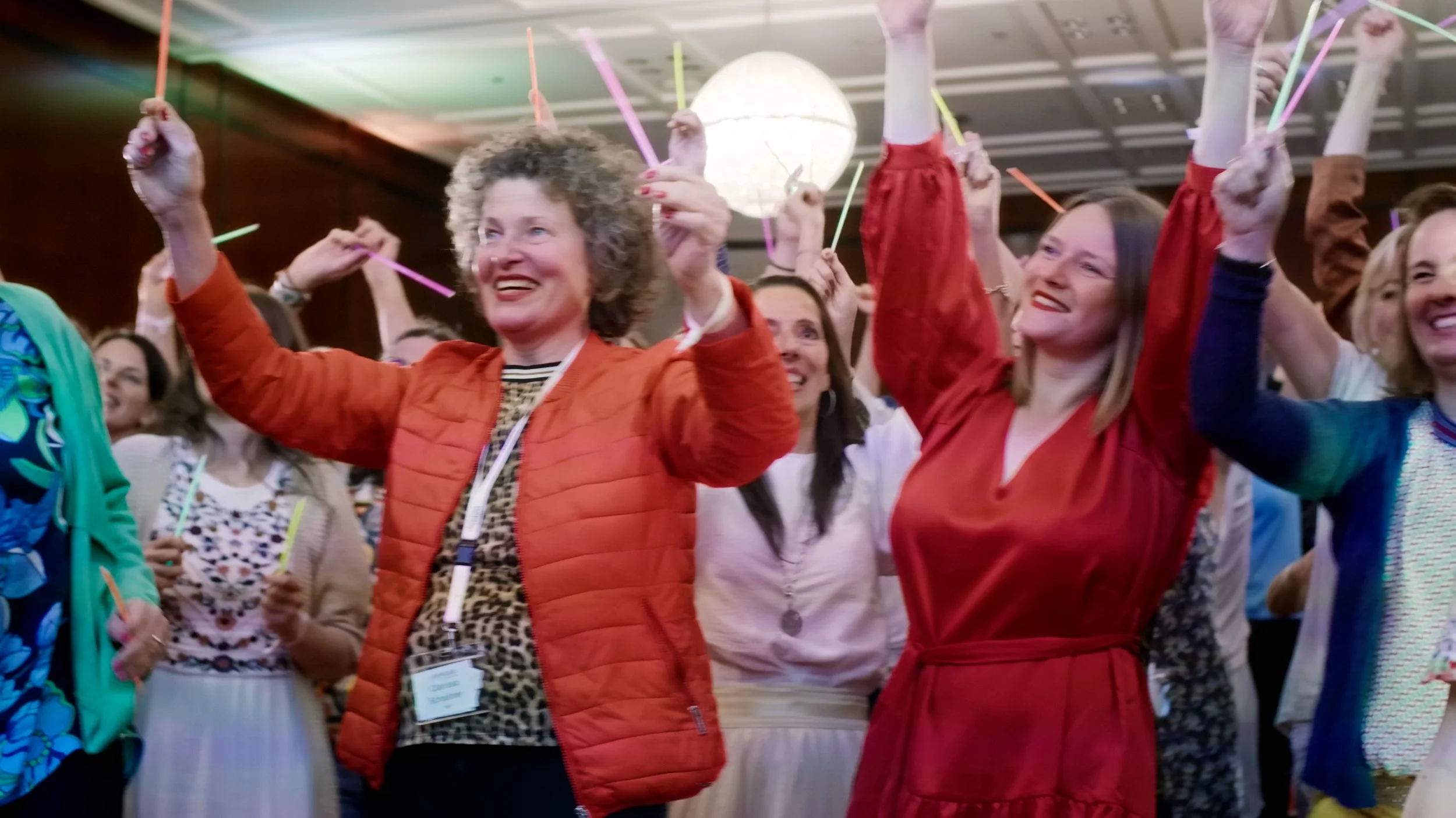 Menschen feiern mit bunten Strohhalmen und Kerzen in der Hand, fröhliche Atmosphäre bei einer Veranstaltung.