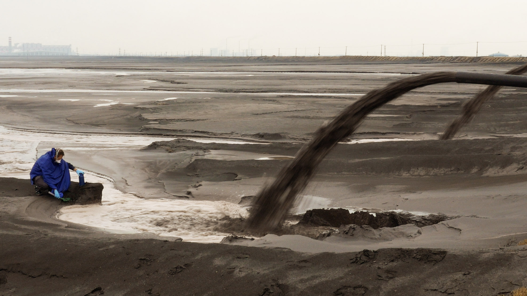   Still from Unknown Fields Division´s film Rare Earthenware. The still shows Liam Young, from Unknown Fields, collecting radioactive mud from the tailings lake at the outflow of Baogang Iron and Steel Corporation. Photo: Toby Smith  