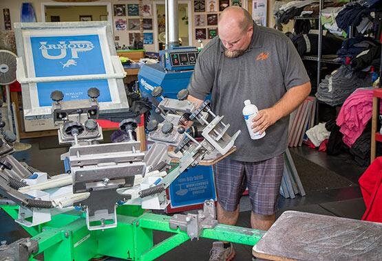  Man performing a screen printing machine maintenance. 