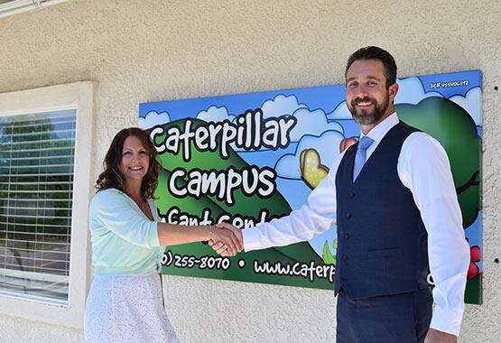  Ryan Richardson and Stacy Shoemaker shaking hands in front of her Caterpillar Campus preschool building 